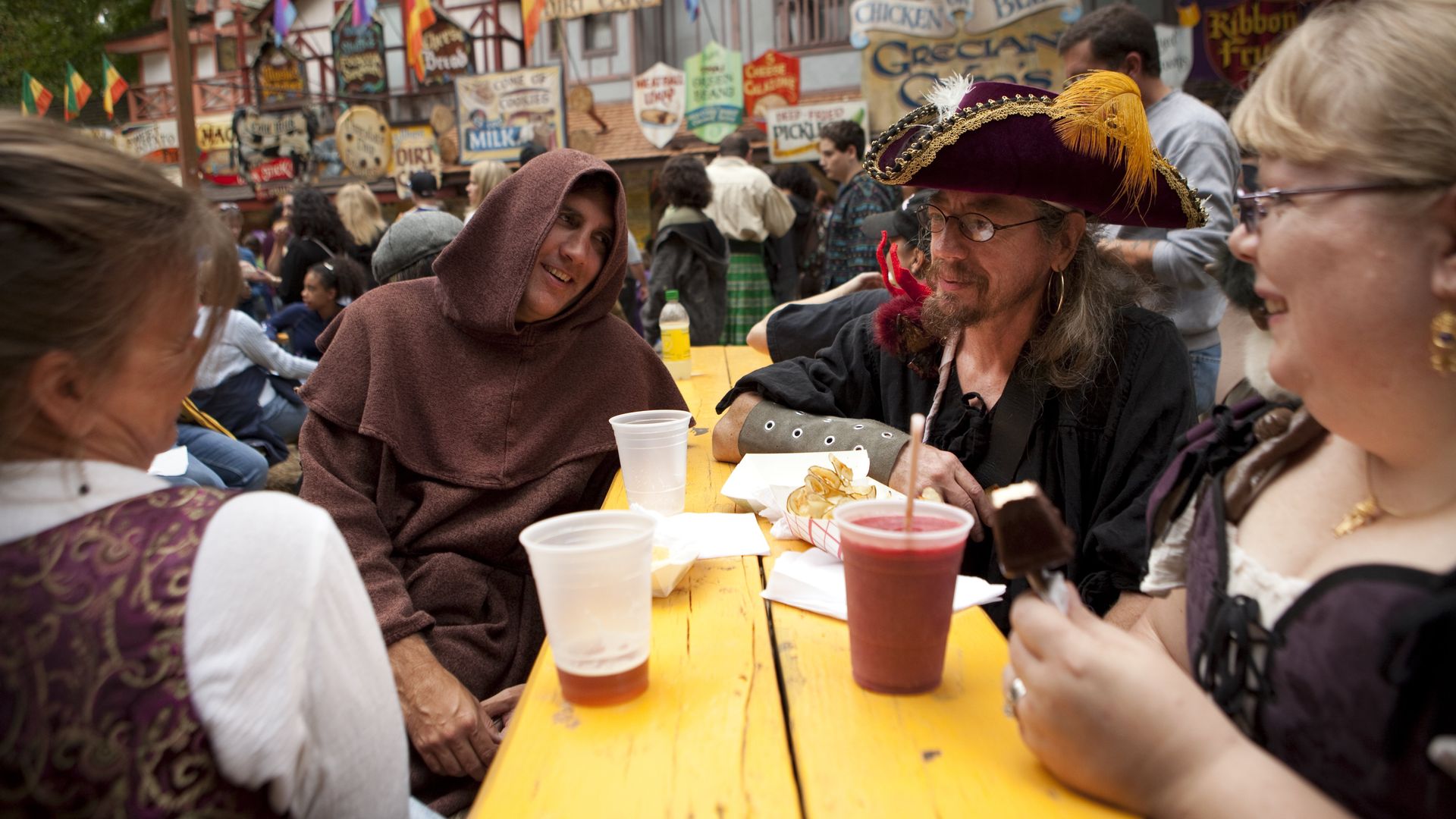 People sit at a table with drinks at the Maryland Renaissance Fair