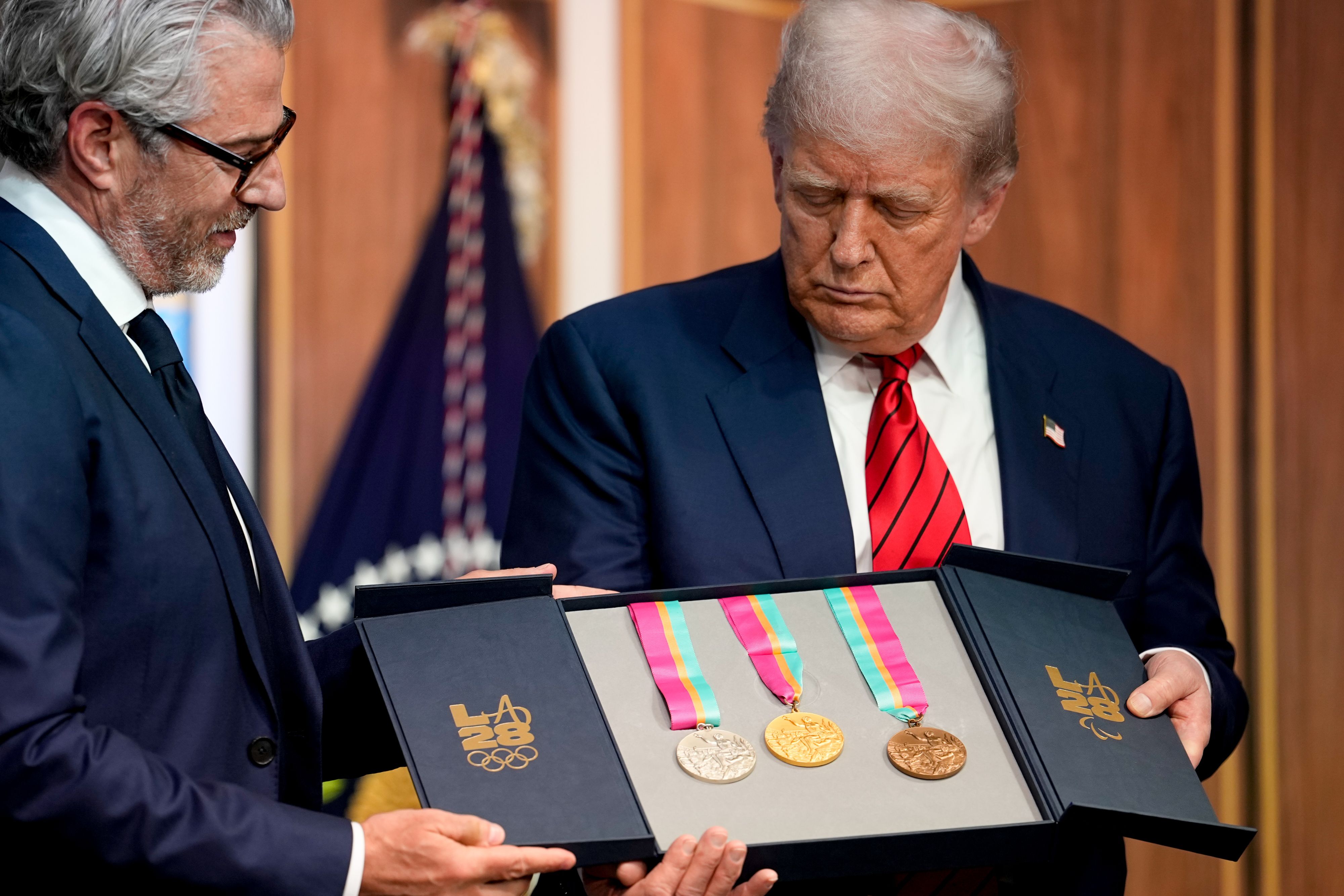 川普身穿藍色夾克、白色襯衫和紅色領帶，手持獎章，與身穿藍色夾克、白色襯衫和藍色領帶的沃瑟曼並肩而立。