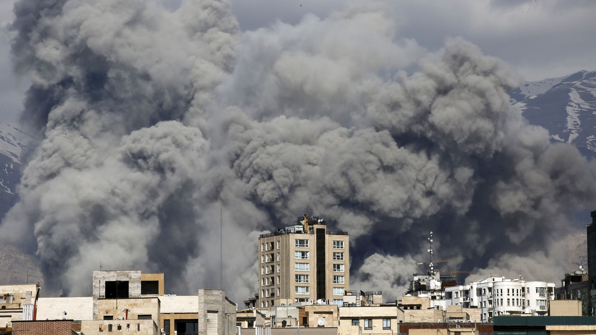 Clouds of smoke are seen behind a city skyline.