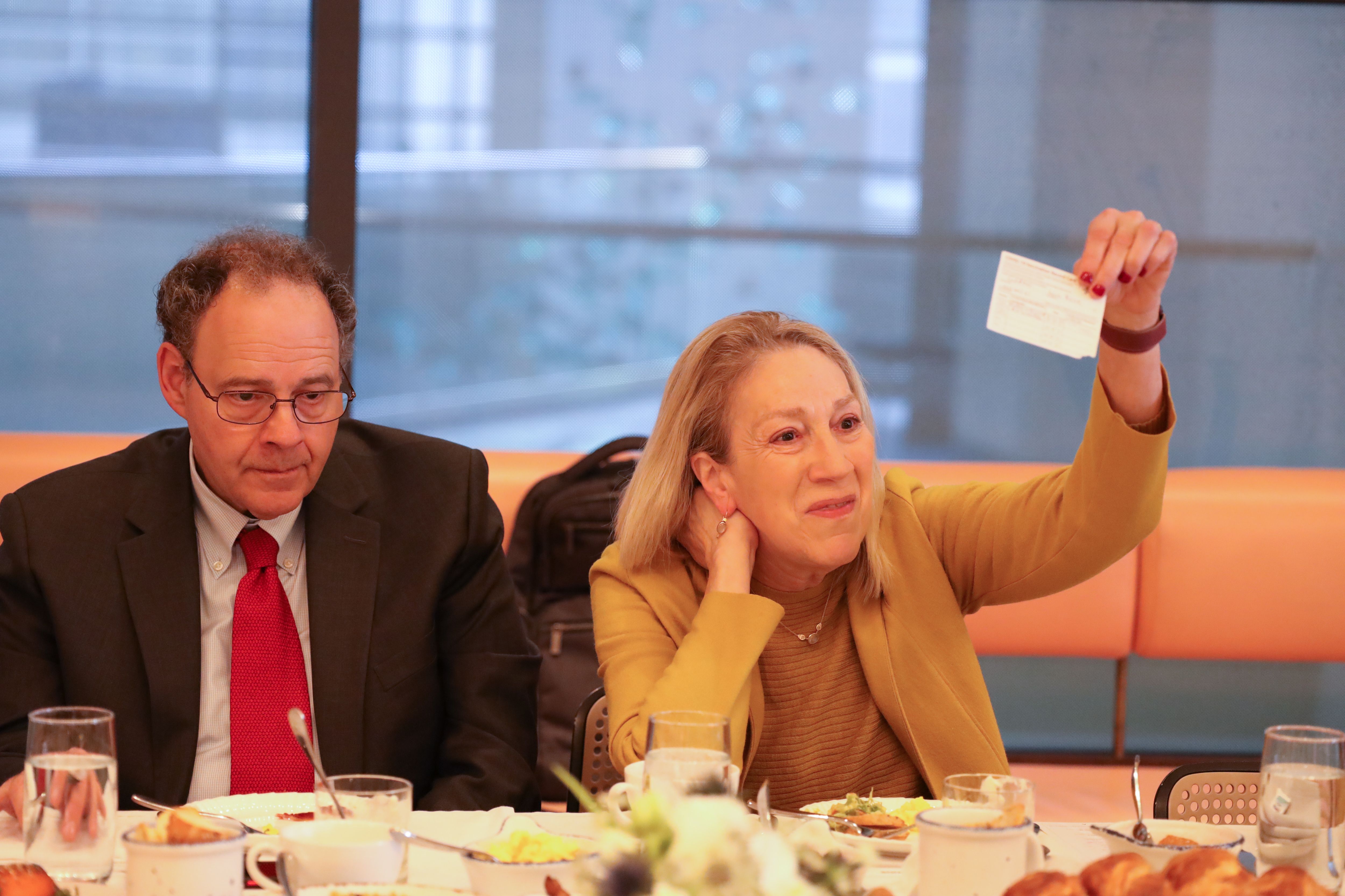 Lynn Goldman holds up an vaccination card during a discussion.