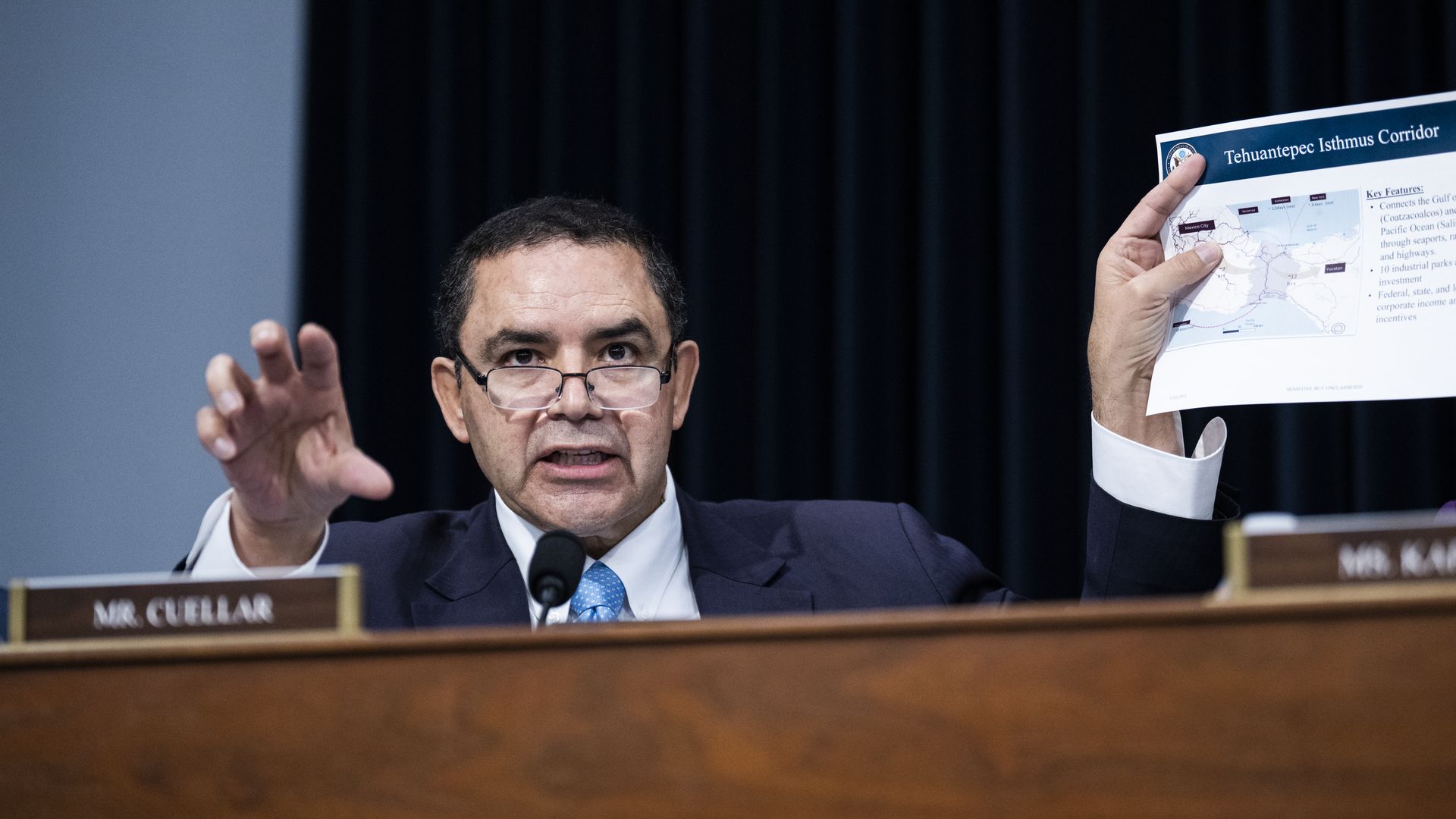 Rep. Henry Cuellar, wearing a blue suit and holding a piece of paper at a committee hearing.