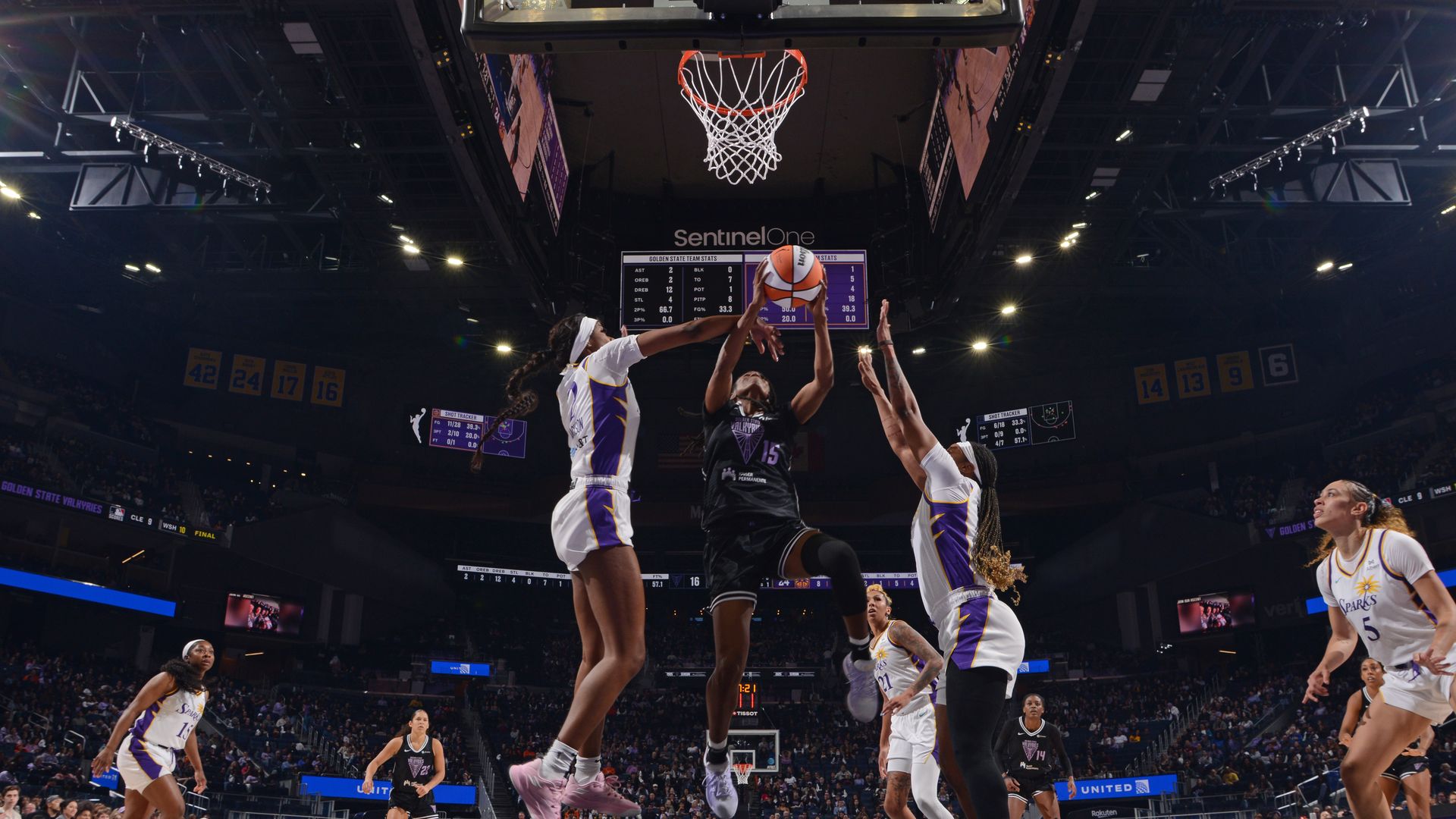 Photo of a Valkyries player driving to the basket while two Sparks players defend