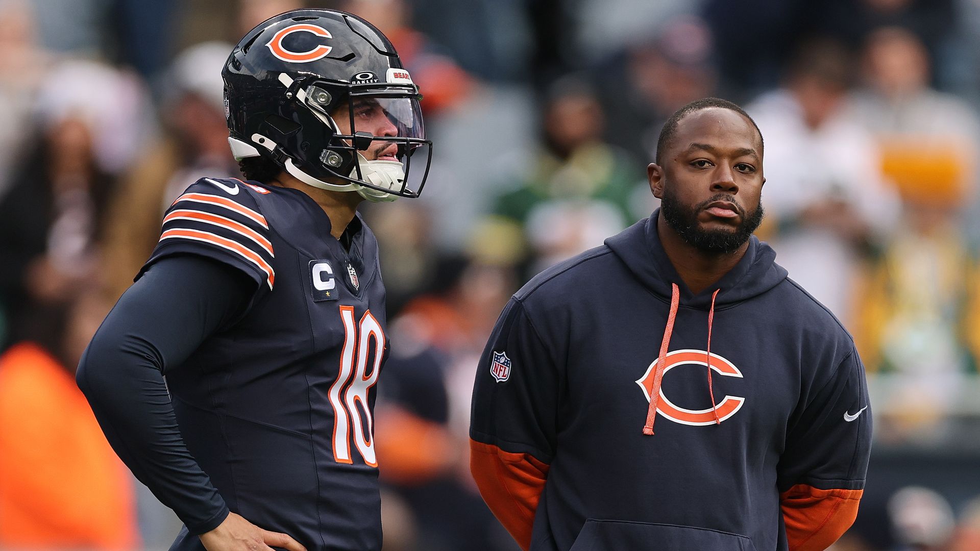 Photo of a football player standing next to a coach on the sidelines of a game 
