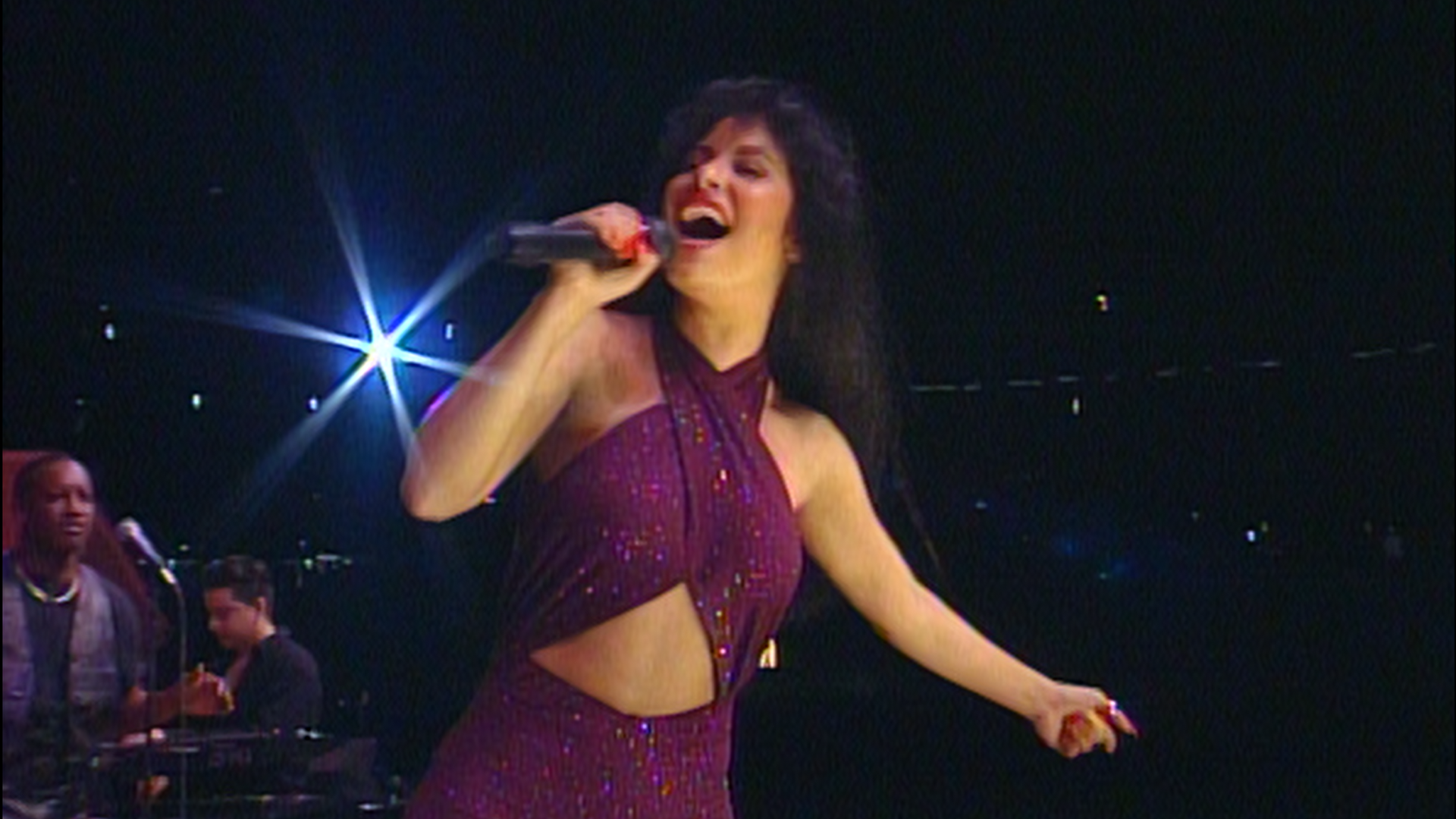 Woman dressed in purple jumpsuit singing