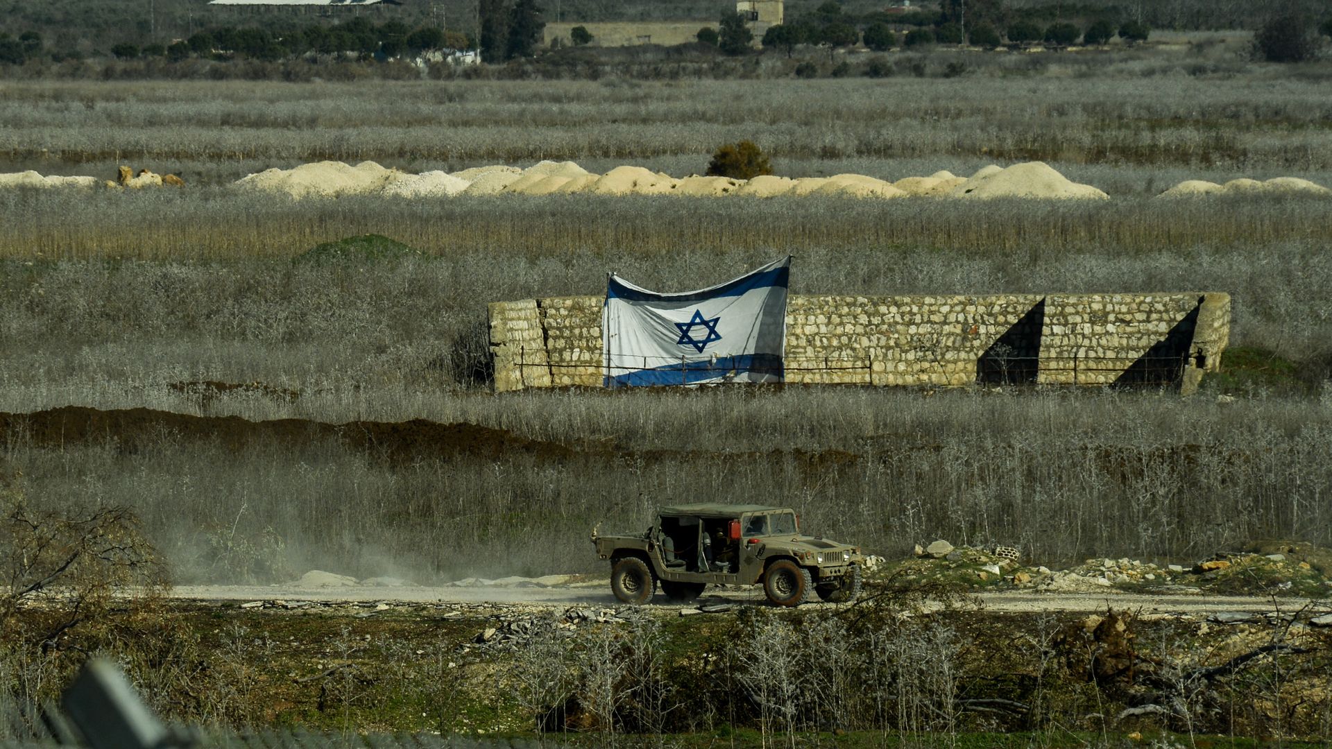 Israeli flag in filed with jeep