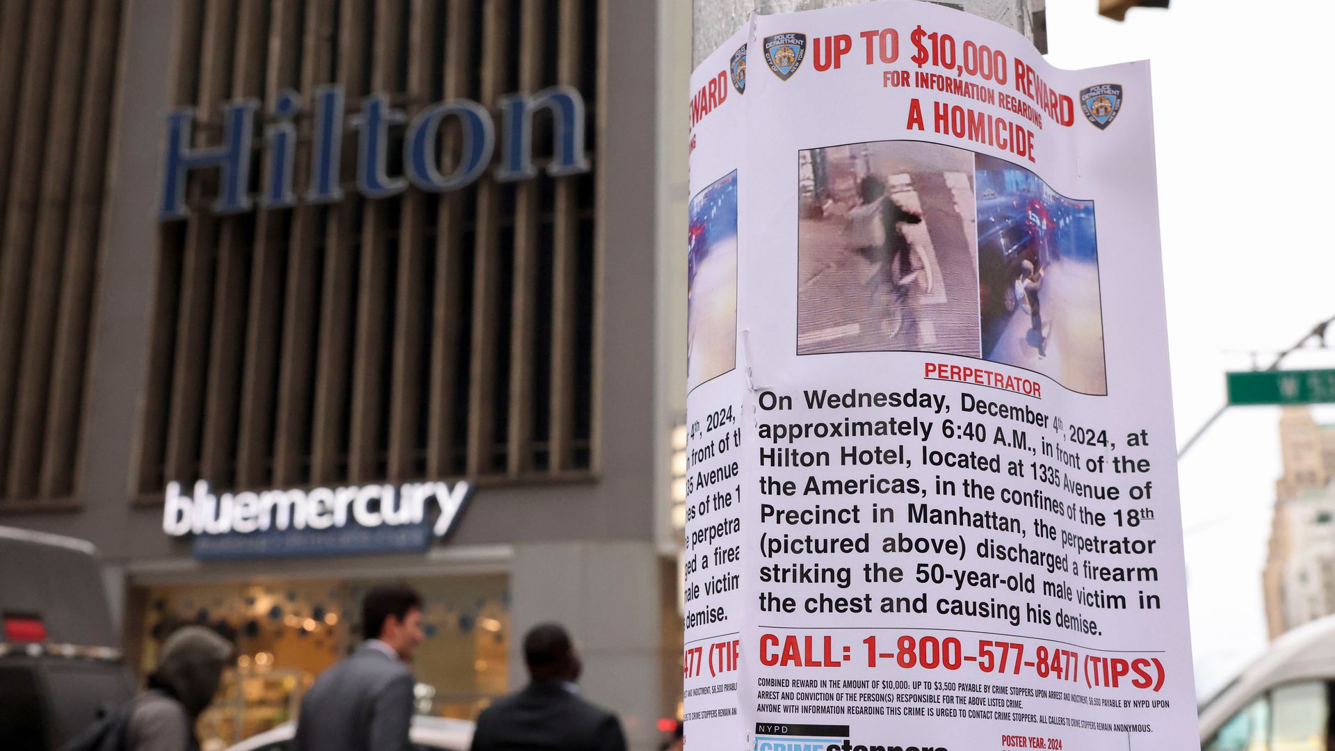 A wanted poster is taped to a pole outside of a Hilton hotel