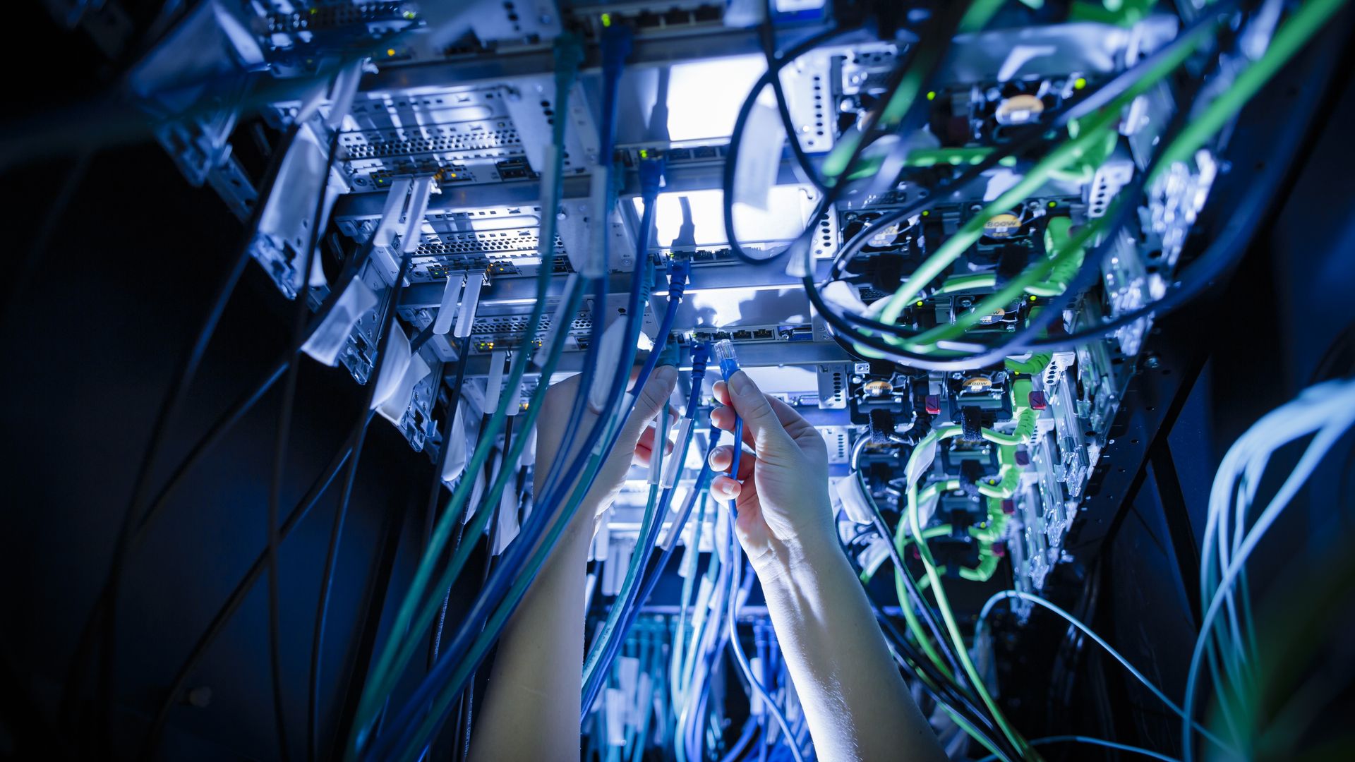Hands pull at cables lit up in blue light.