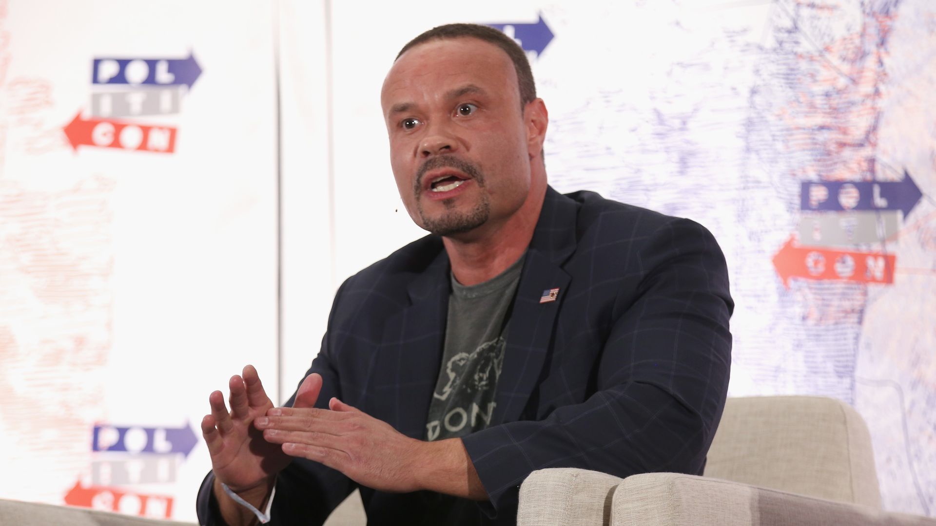 Dan Bongino gestures as he sits and speaks during  Politicon 2018.