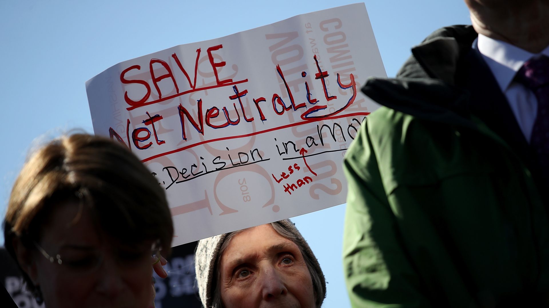 A woman holds a sign that says "Save net neutrality"