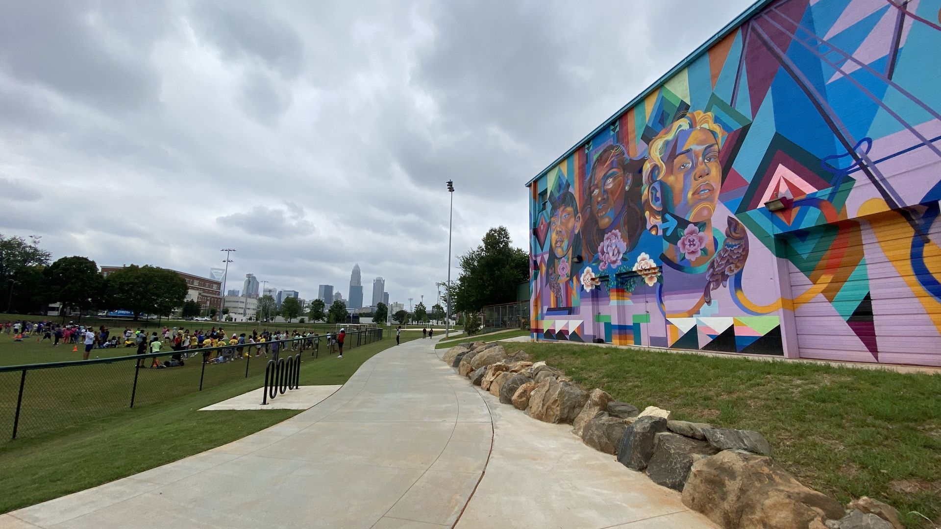 The Charlotte skyline in the background with a baseball field to the left and a mural to the right in Independence Park.
