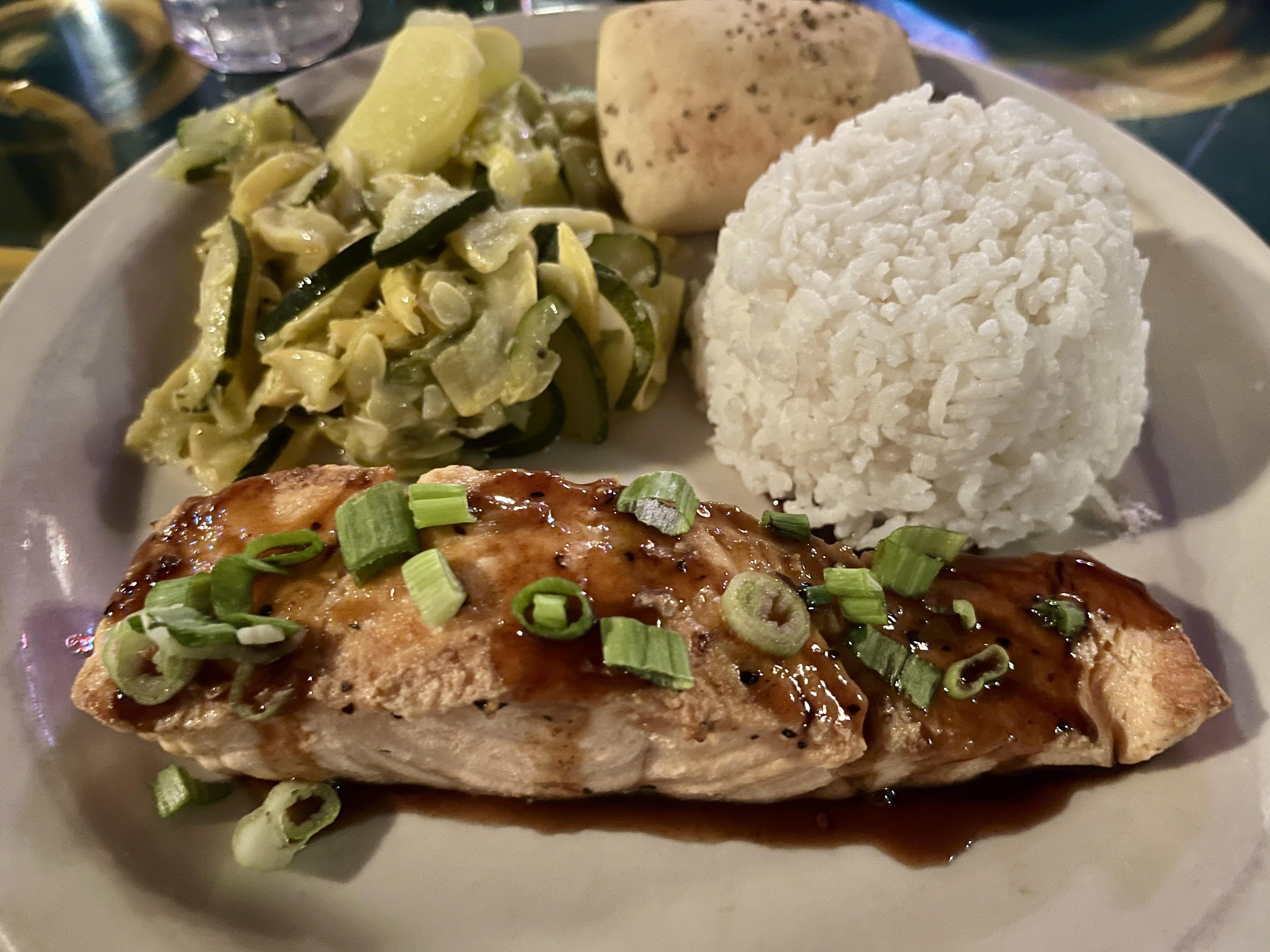 A soy glazed salmon filet with a ball of white rice and veggies.