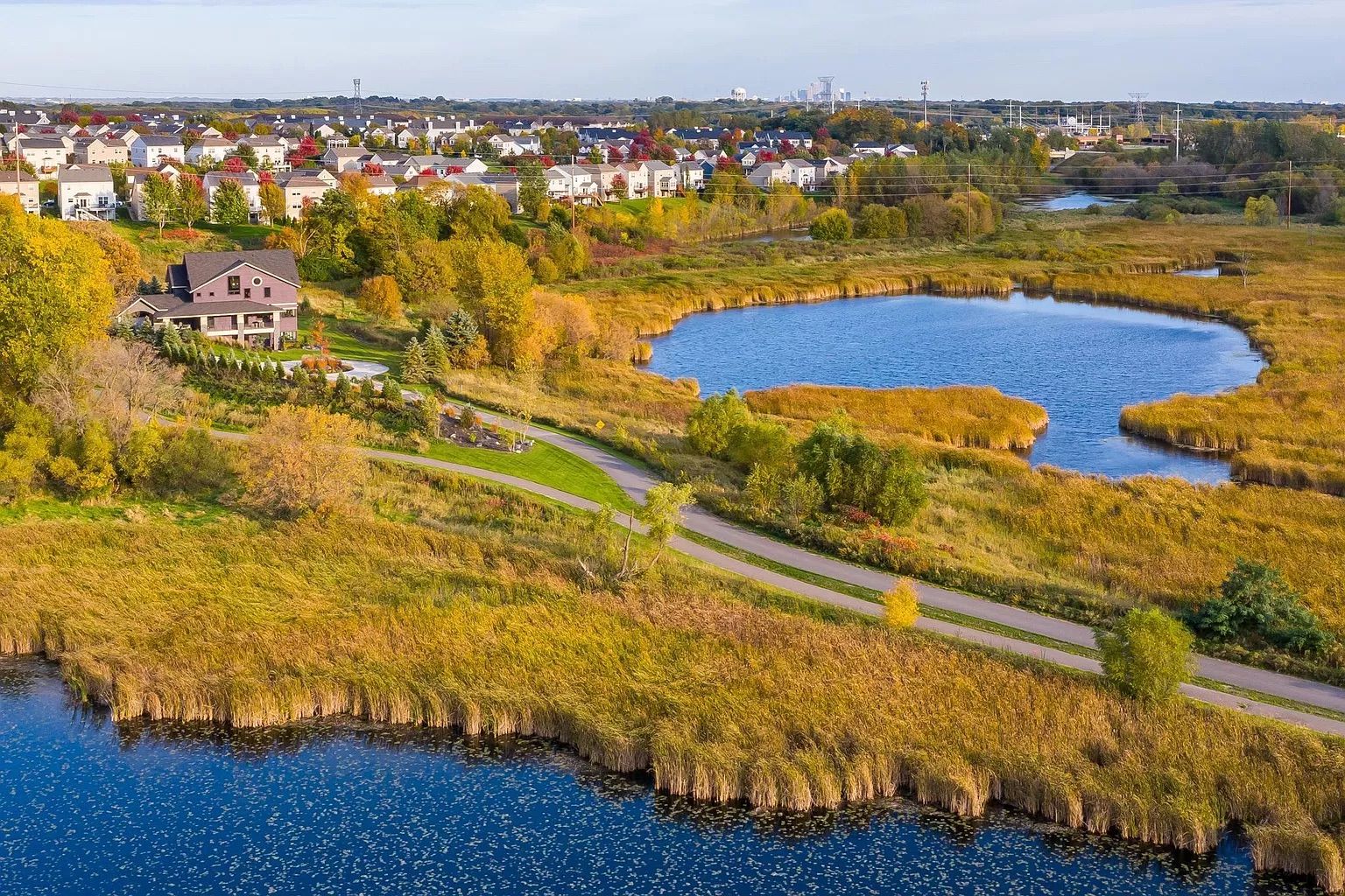 A drone shot of the purple mansion with a lake visible next to it.