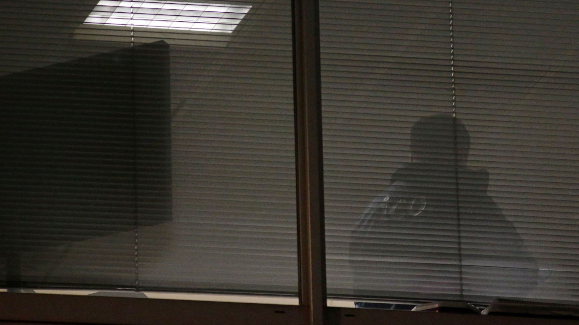 A man is seen through blinds inside the offices of Cambridge Analytica in central London.