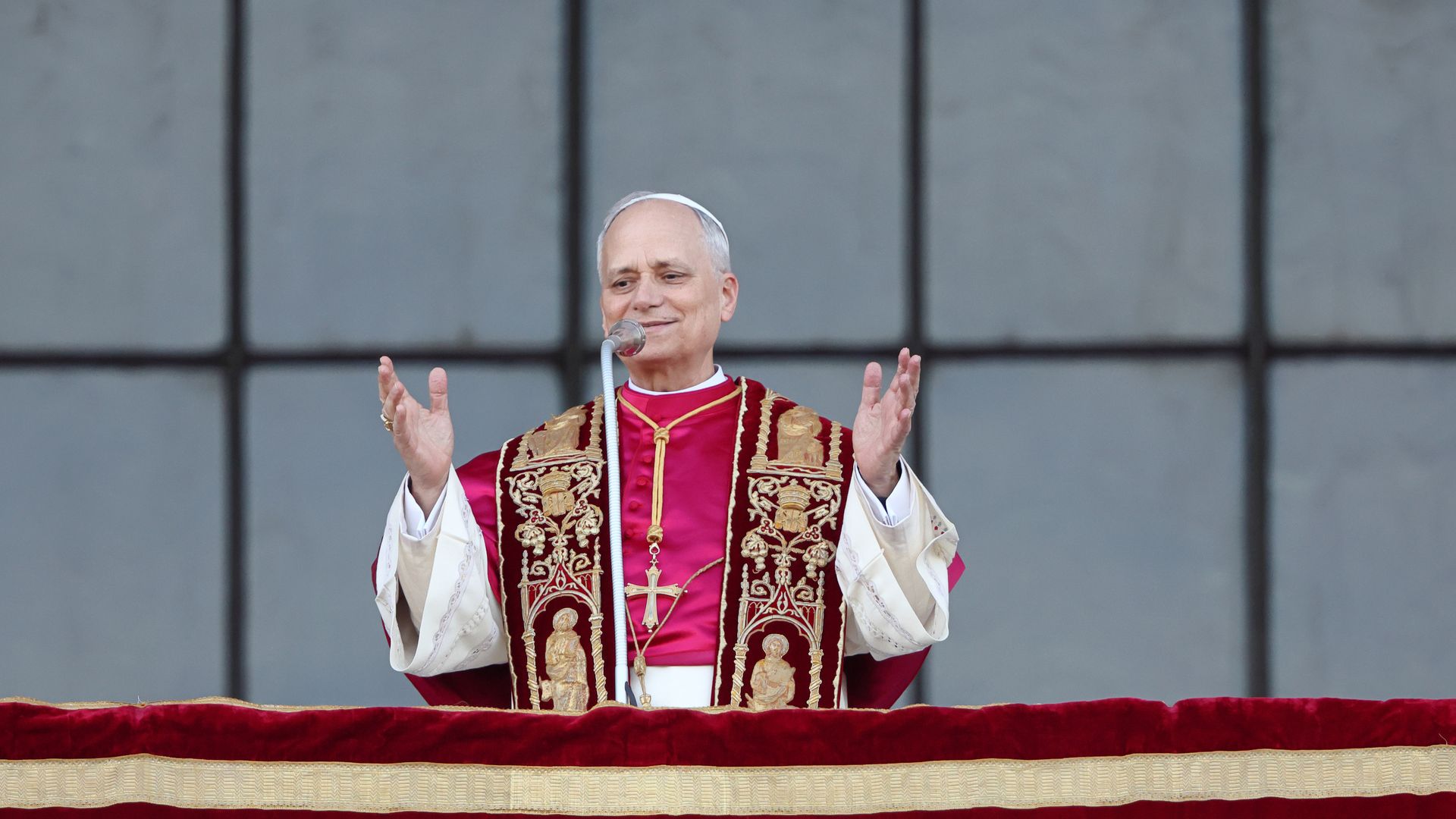 Pope Leo XIV with hands outstretched behind mic.