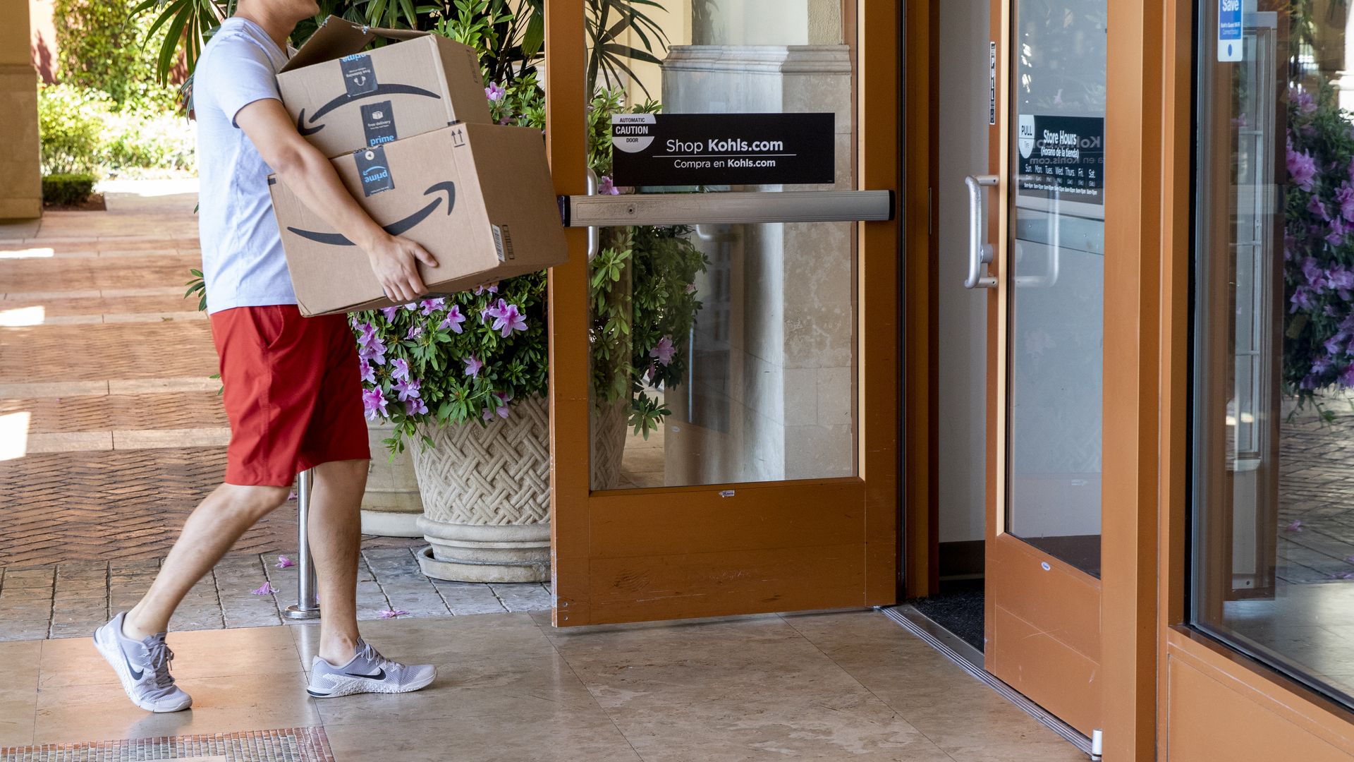 Shopper carrying Amazon boxes into Kohl's store