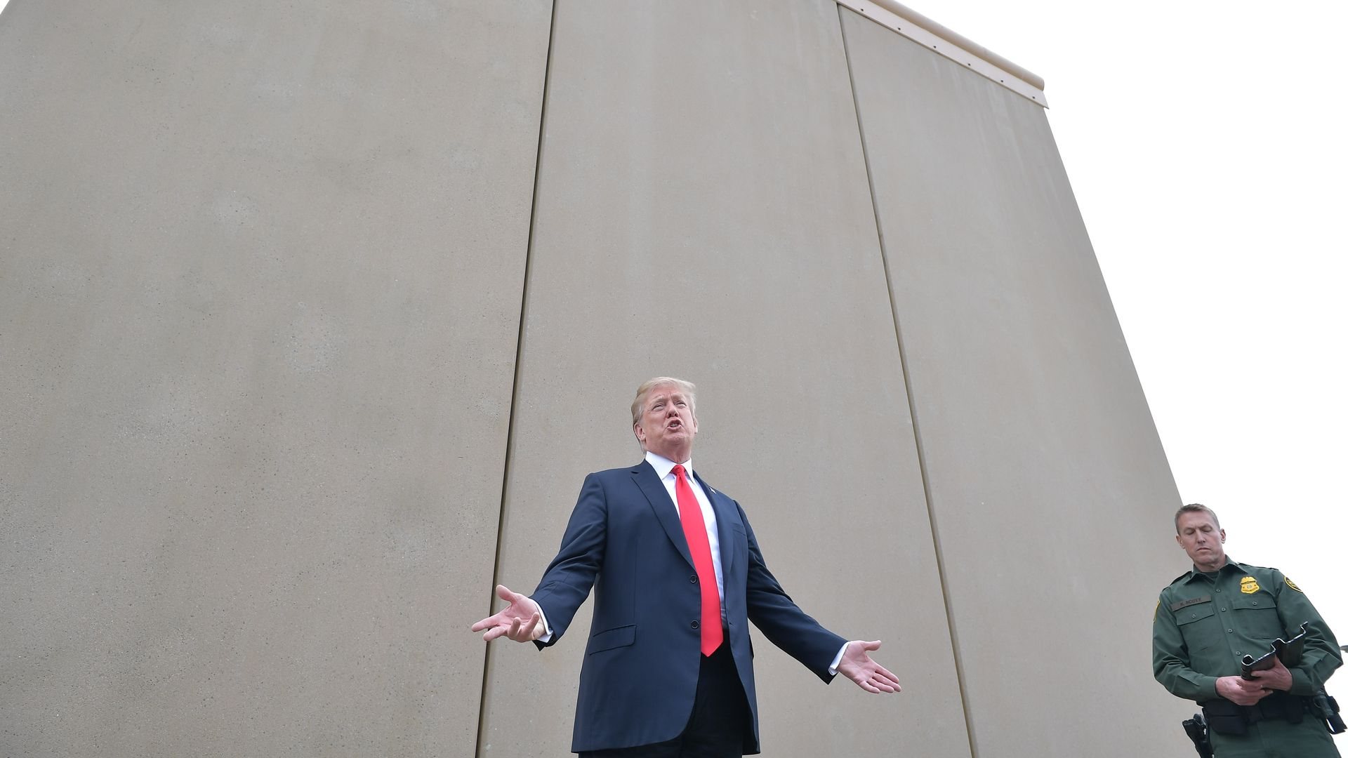 In this image, Trump stands in front of a border wall prototype.
