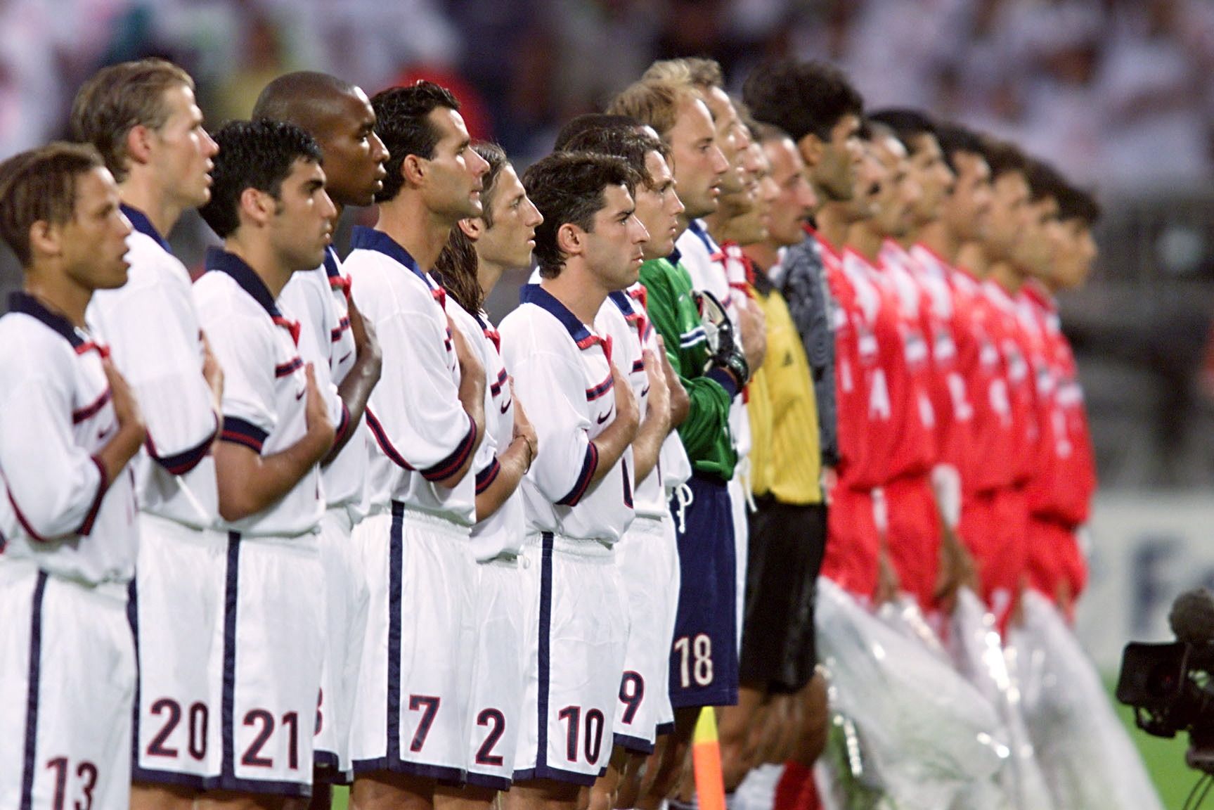 Soccer players in red and white stand for anthems