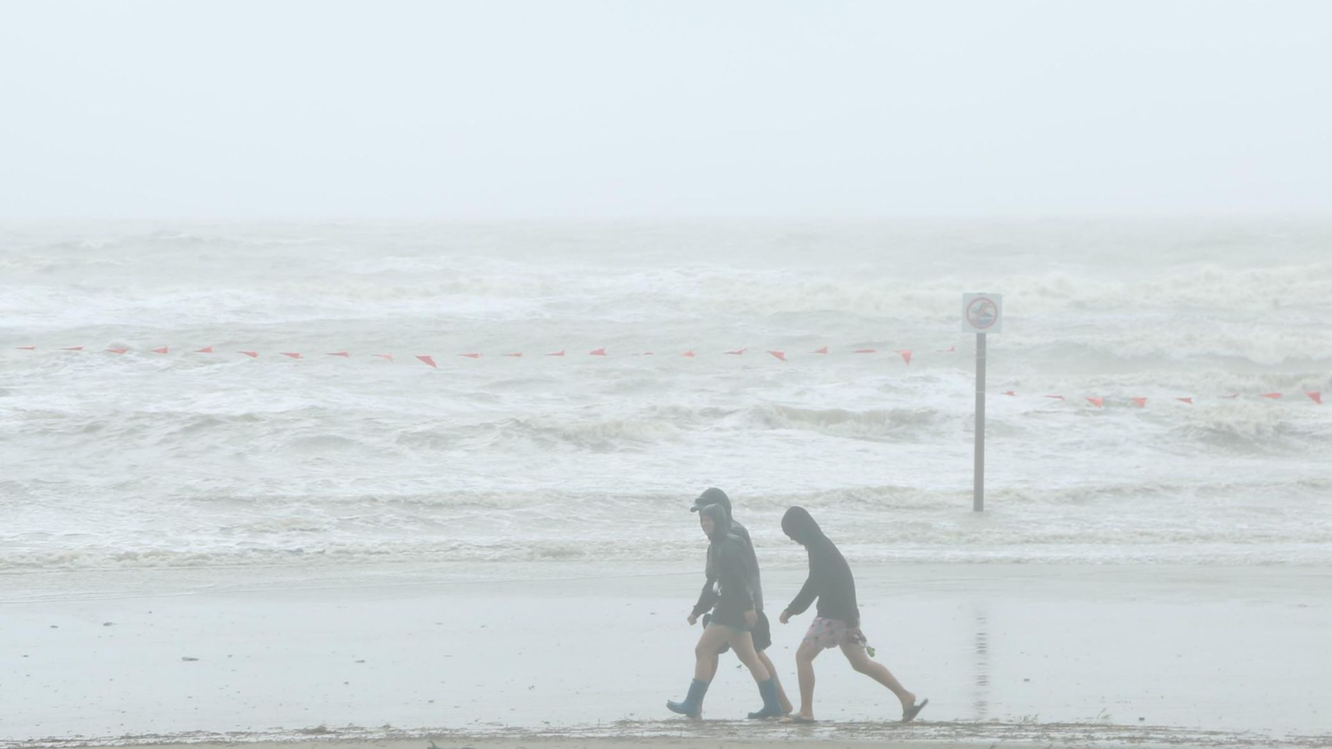 People walk on the beach at Galveston Island as tropical storm Beta will make landfall near Matagorda Bay on September 21, 2020 in Galveston, Texas.