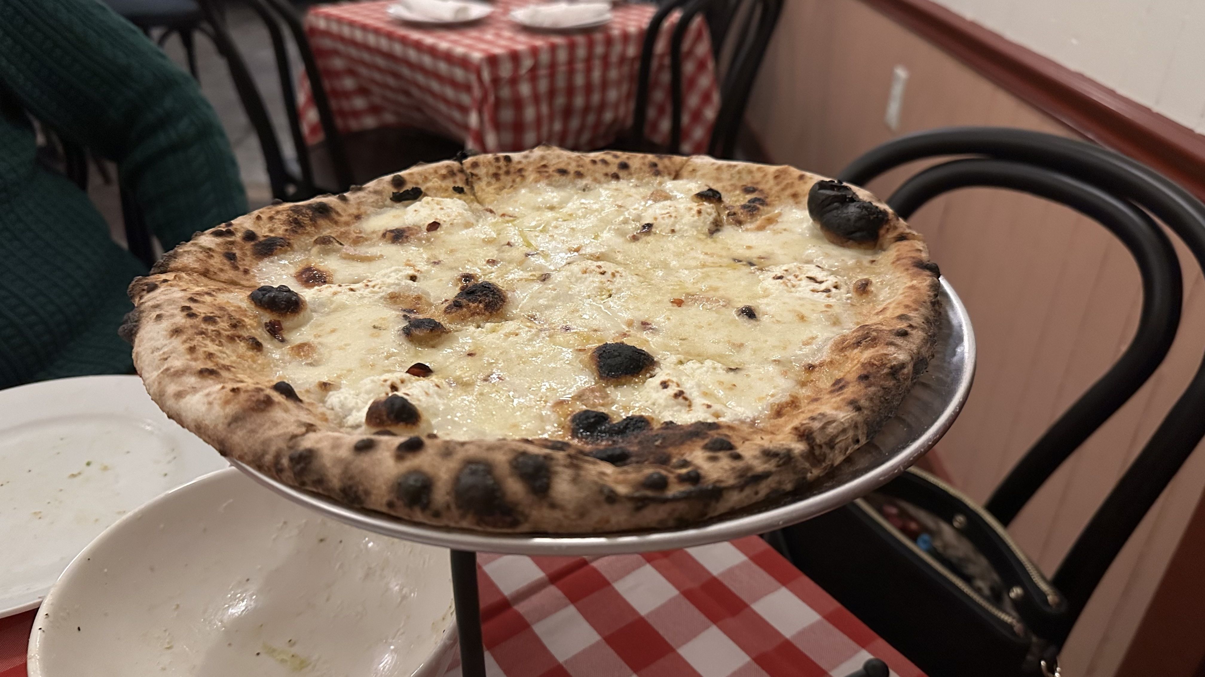 A white pie sits atop a checkered tablecloth-covered table.