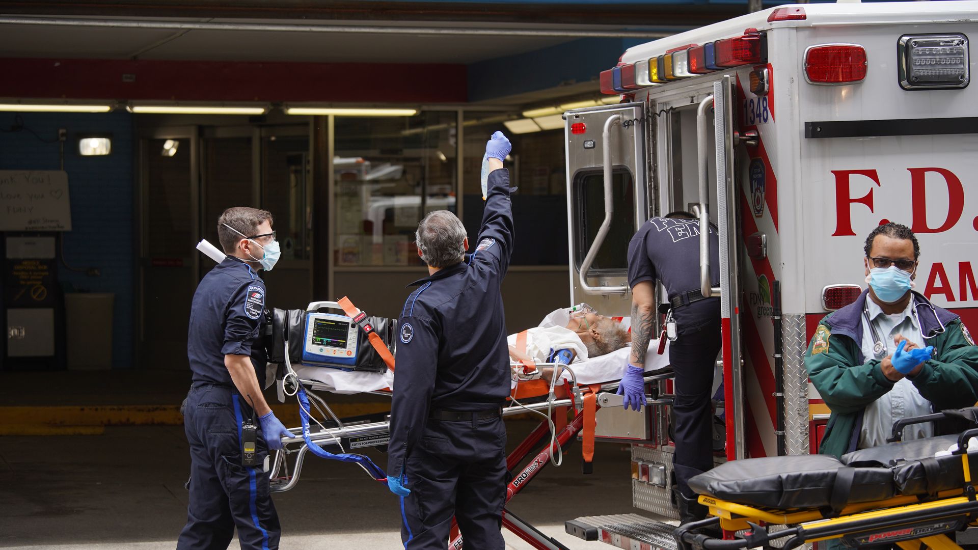 In this image, a person is carried into an ambulance on a stretcher