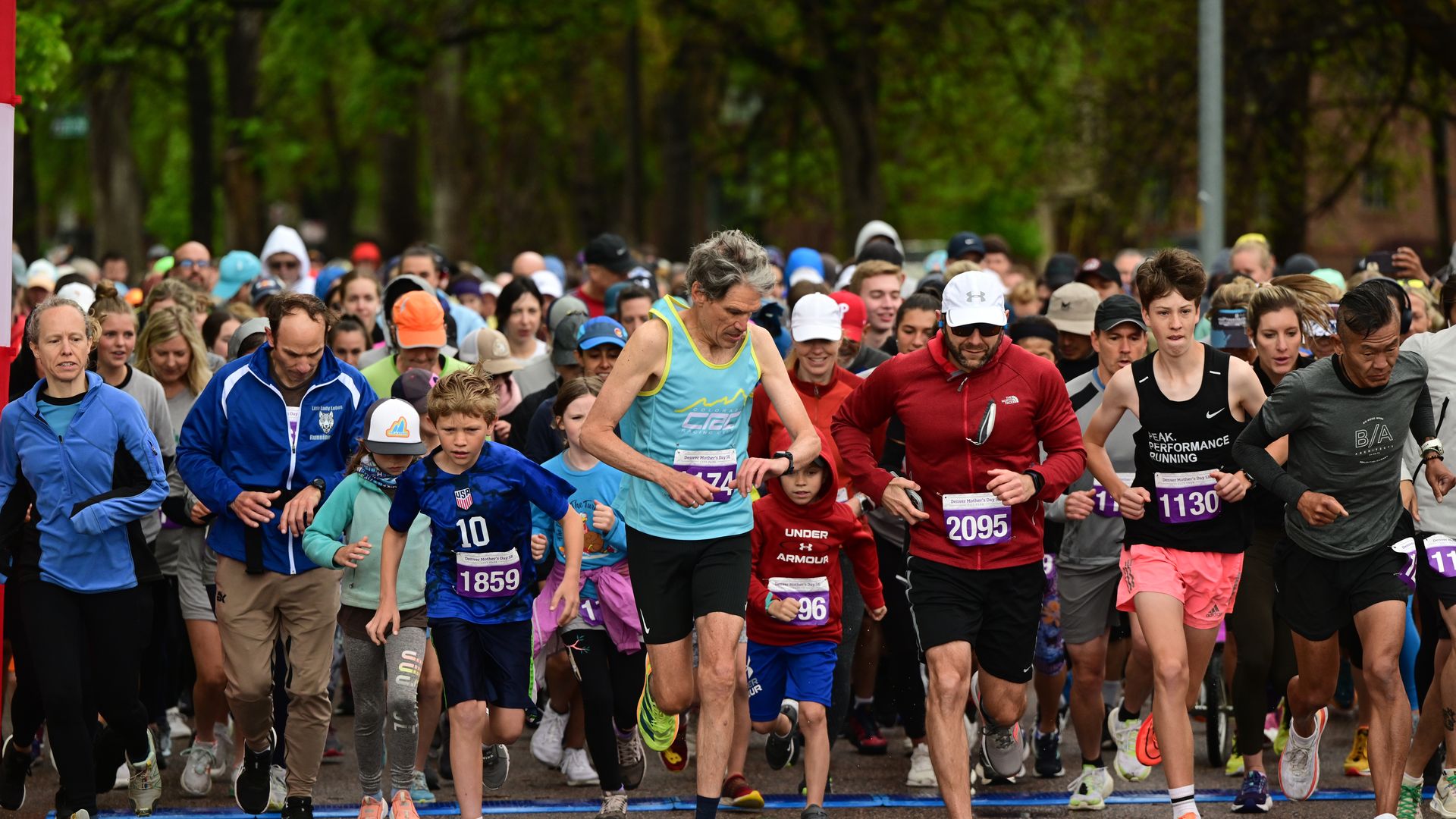 A crowd of runners takes off at the start of a race. 