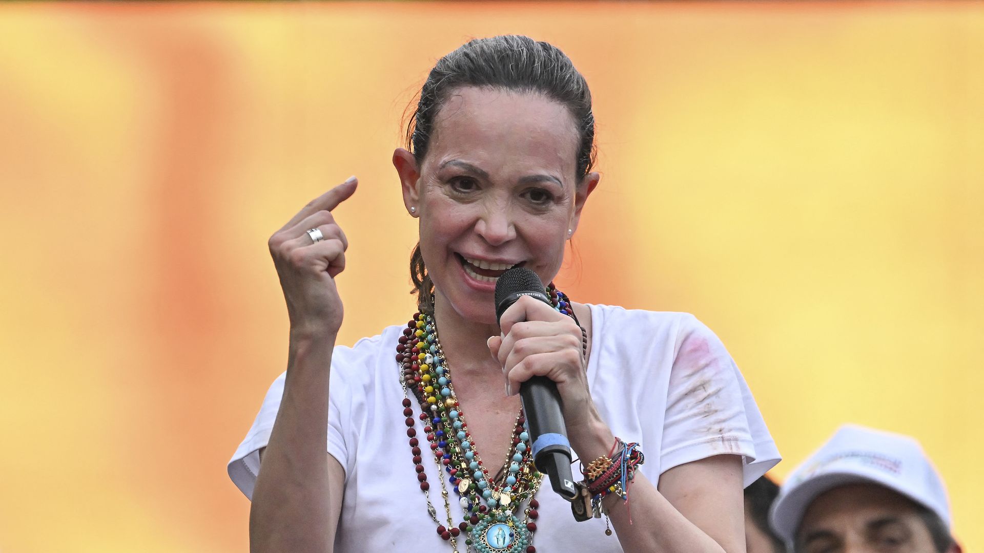 Maria Machado speaks into a microphone and gestures with her right index finger