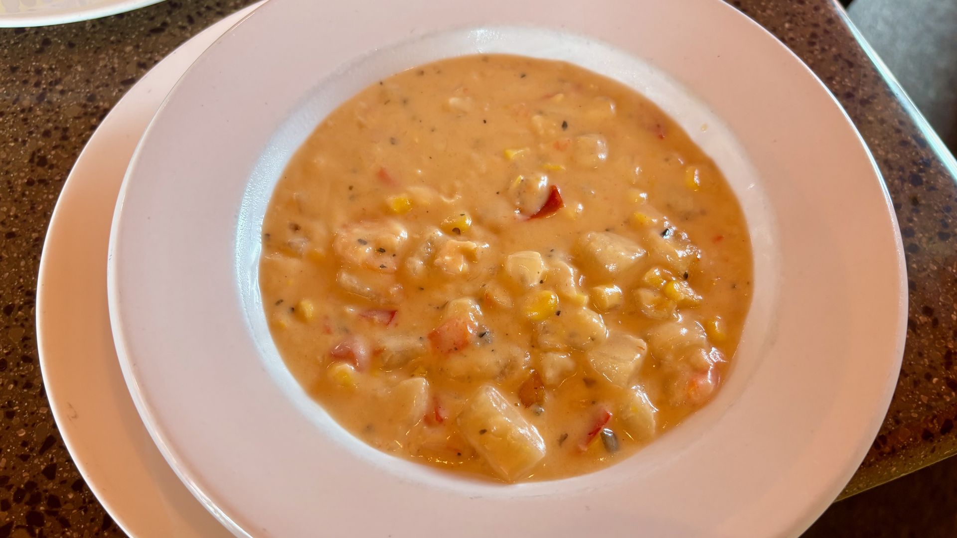 An overview of shrimp and corn chowder soup in a white bowl