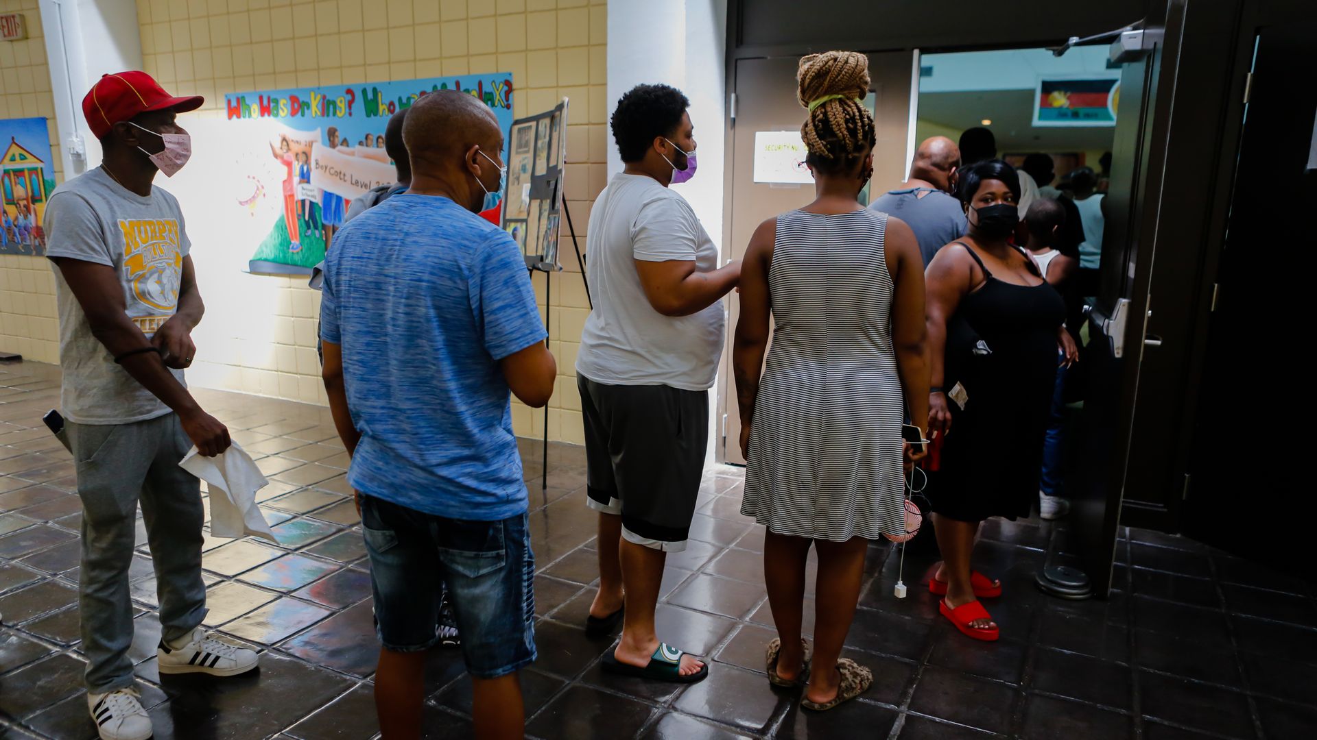 People stand in line through a doorway at a community center.