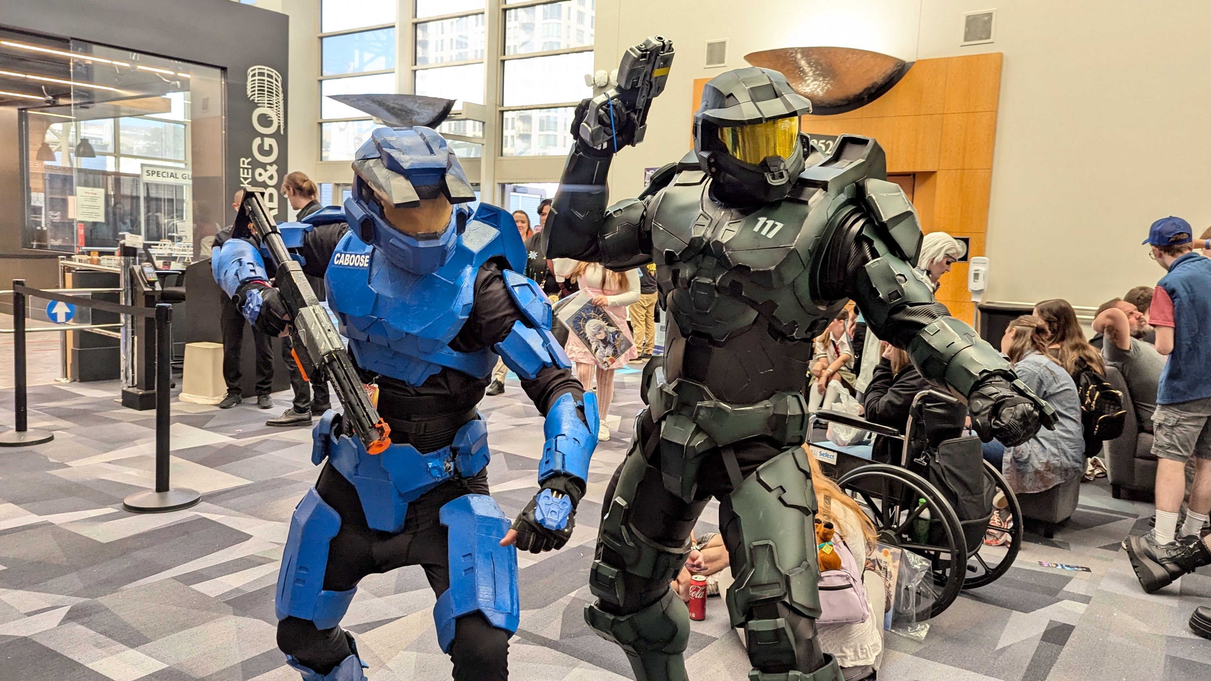 Two people dressed as fully-armored sci-fi heroes Michael J. Caboose and Master Chief in a convention center.