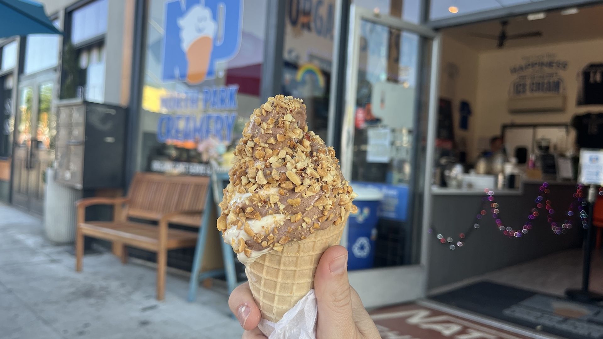 A twist soft-serve ice cream cone with crushed peanuts on top. 