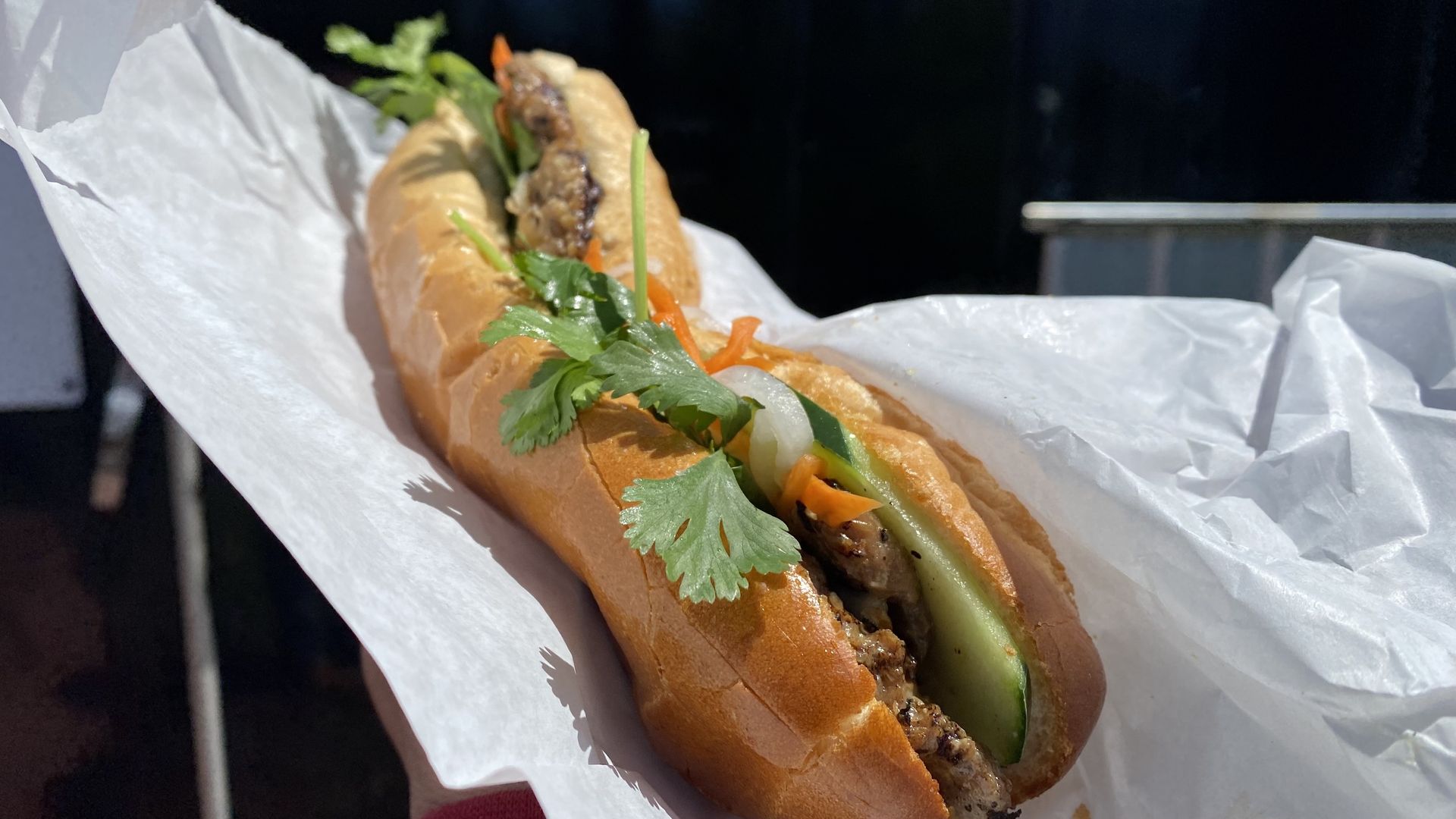 A photo of a long sandwich on French bread wrapped in paper. 