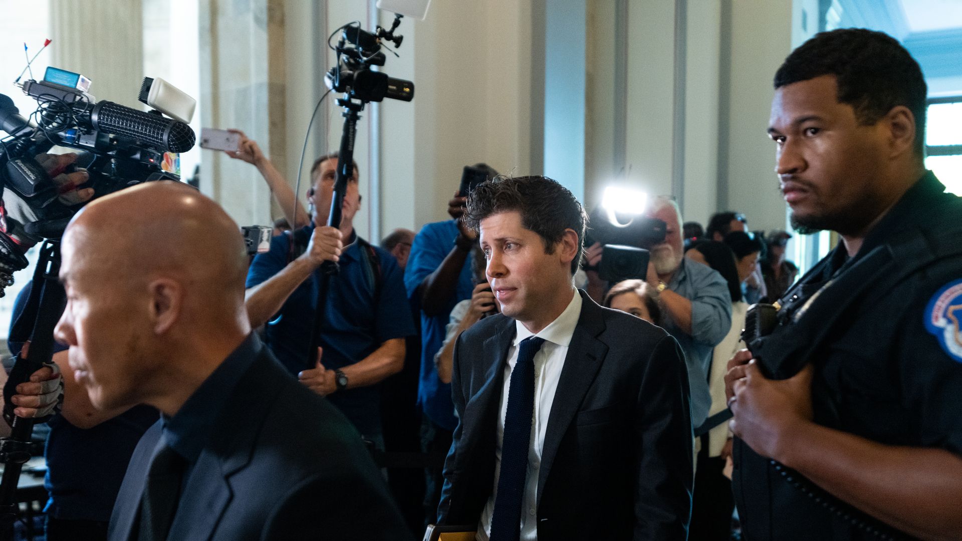 OpenAI CEO Sam Altman flanked by press and bodyguards on Capitol Hill