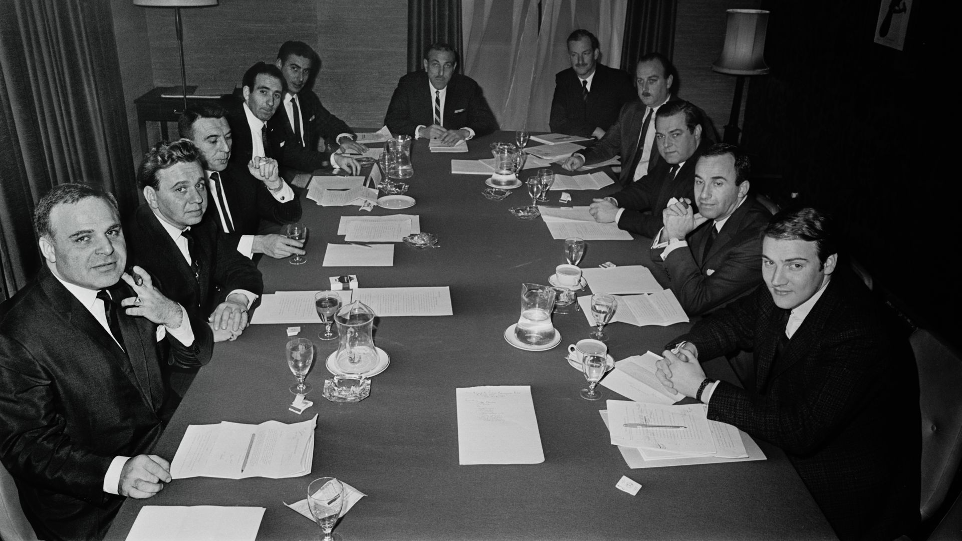 Black and white photo of a group of men sitting at a table with papers