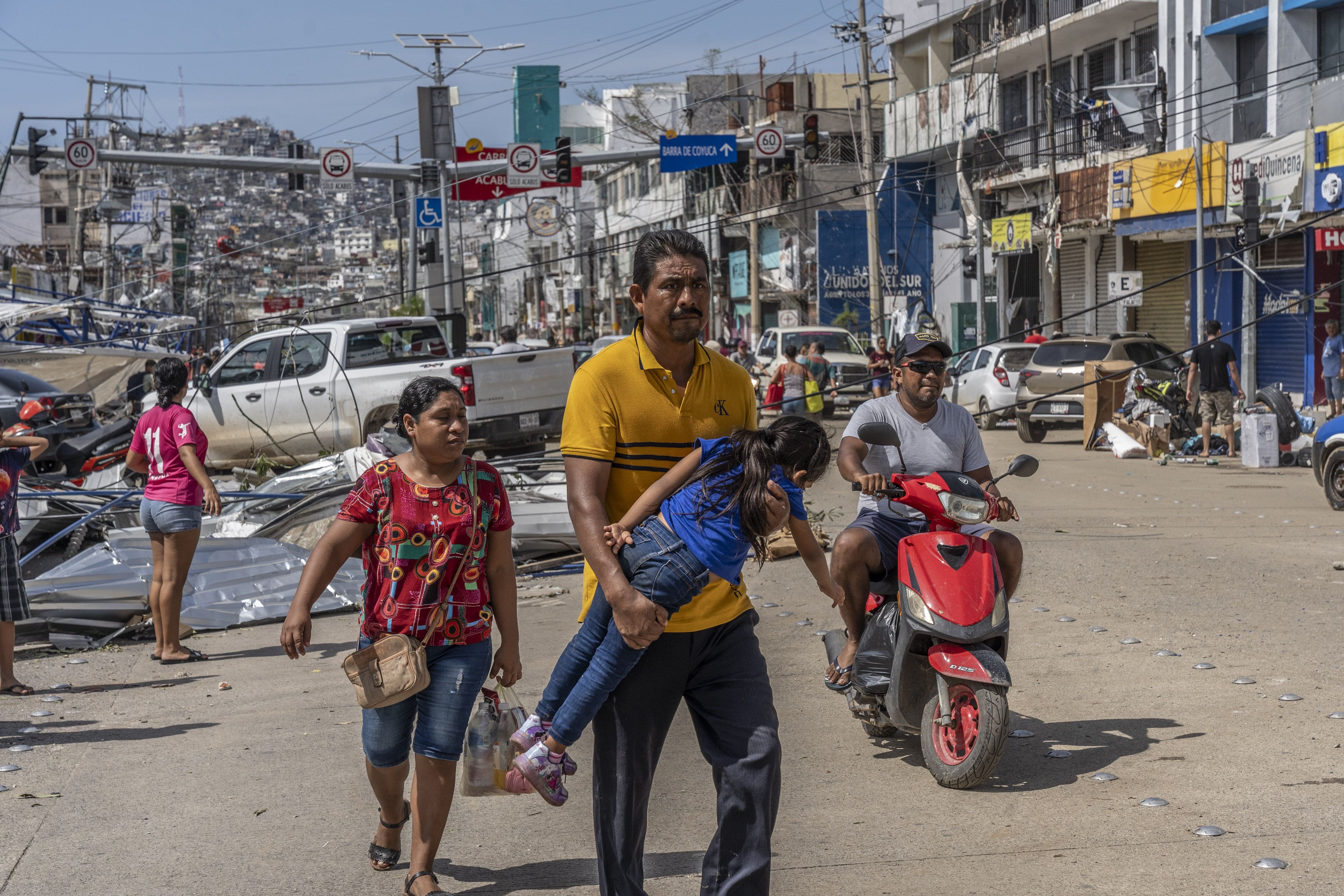 A resident carries his daughter in the aftermath of Hurricane Otis in Acapulco, Guerrero state, Mexico, on Thursday, Oct. 26, 2023. 