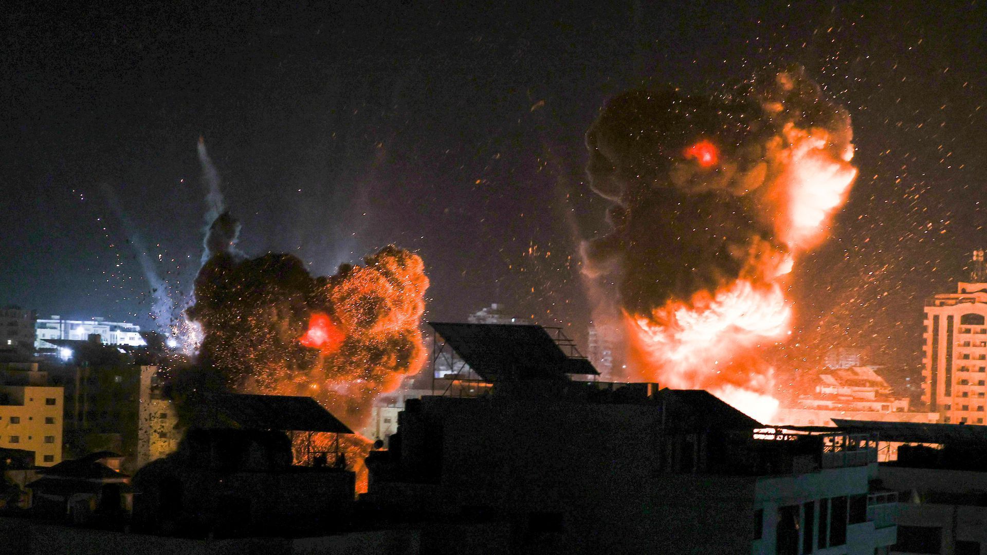 Explosions light-up the sky above buildings in Gaza City as Israeli forces shell the Palestinian enclave early on May 18.