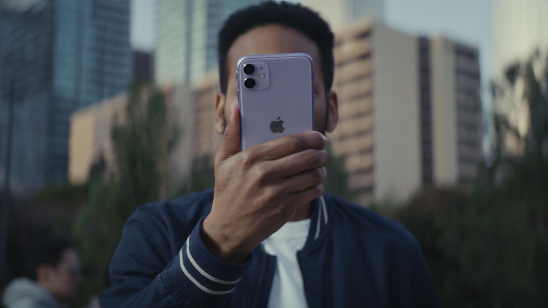 A man's face is obscured by an Apple iPhone 11