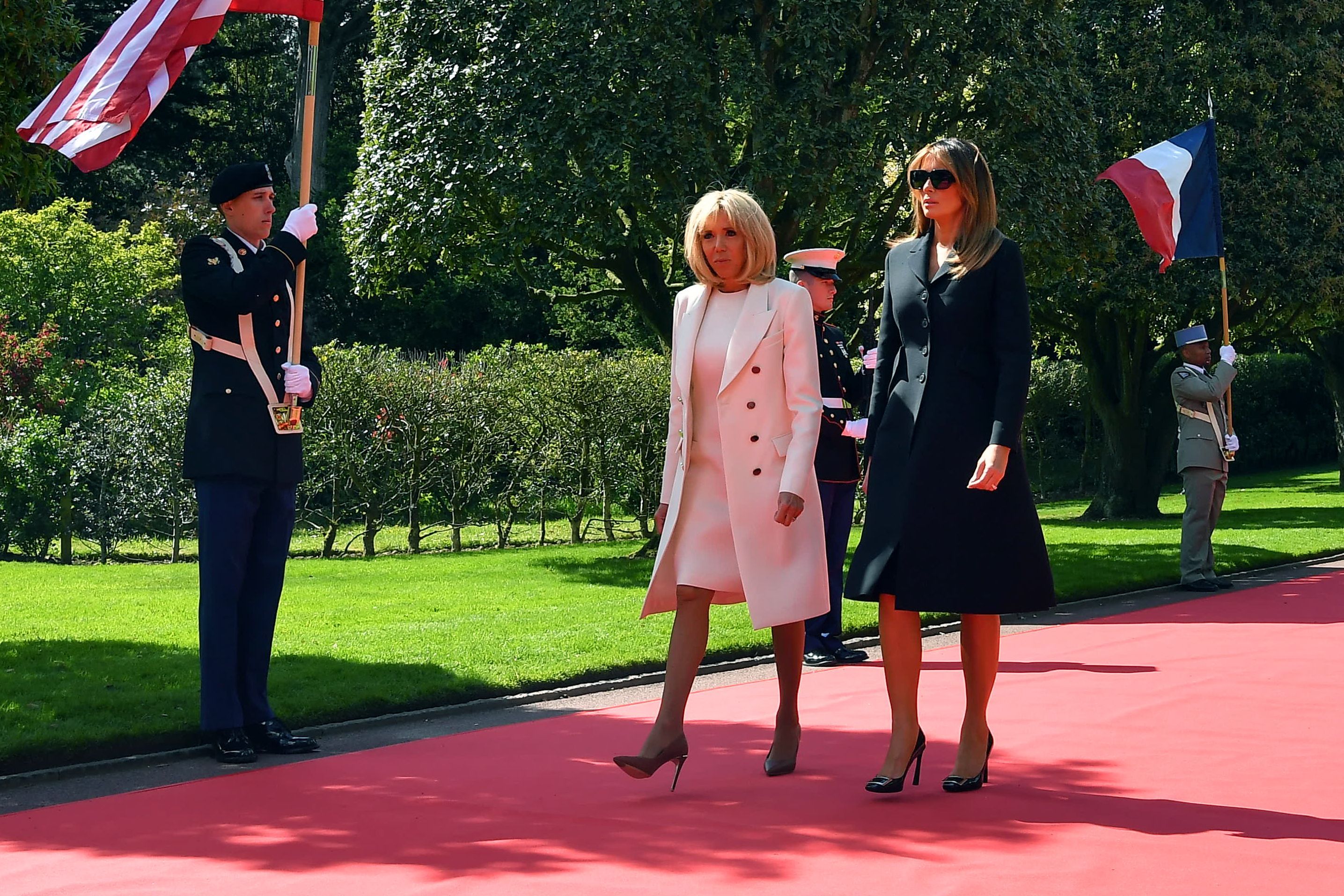 French President's wife Brigitte Macron (L) and US First Lady Melania Trump walk on the red carpet during a French-US ceremony at the Normandy American Cemetery.