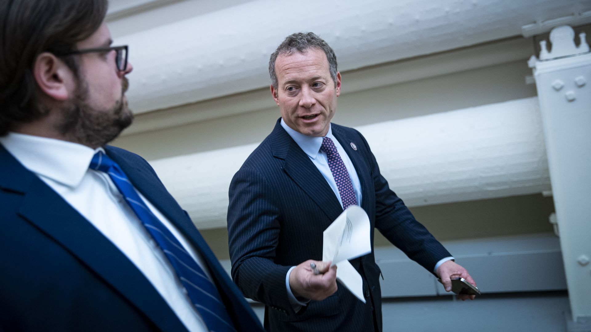 Rep. Josh Gottheimer, wearing a blue suit and walking in the Capitol's basement hallway.