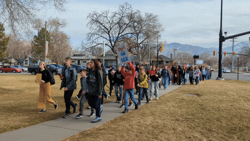 Middle schoolers march through a park with anti-ICE protest signs 