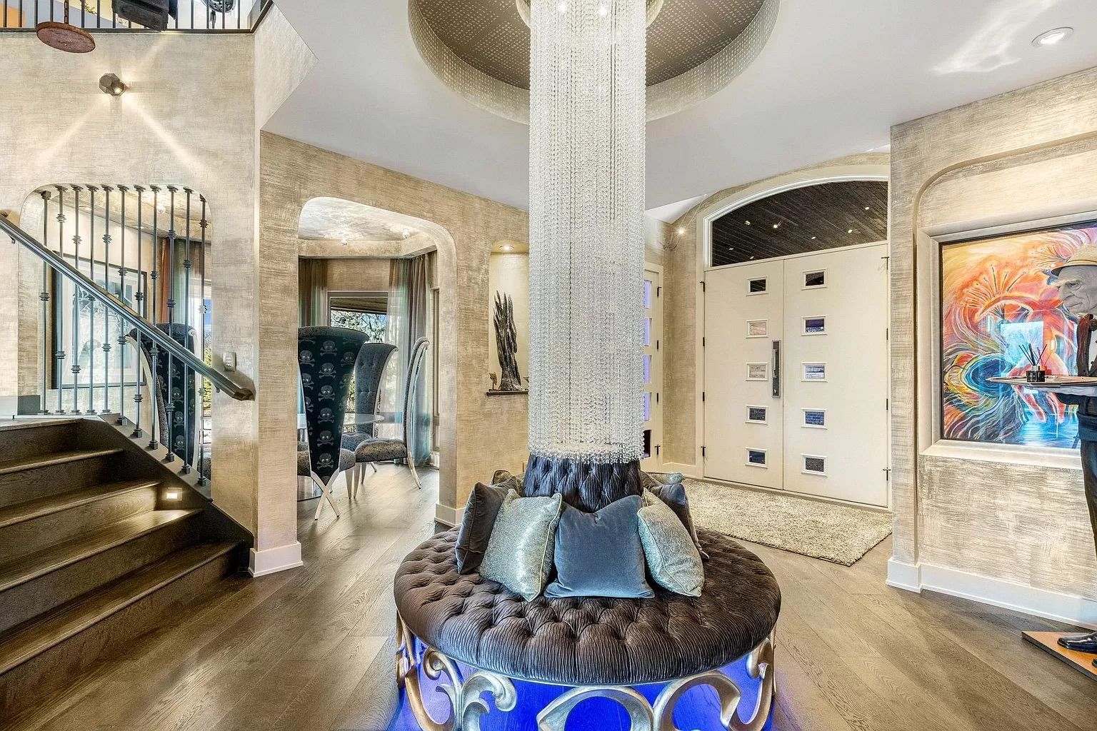 The inside of the mansion with gray walls and a hanging chandelier