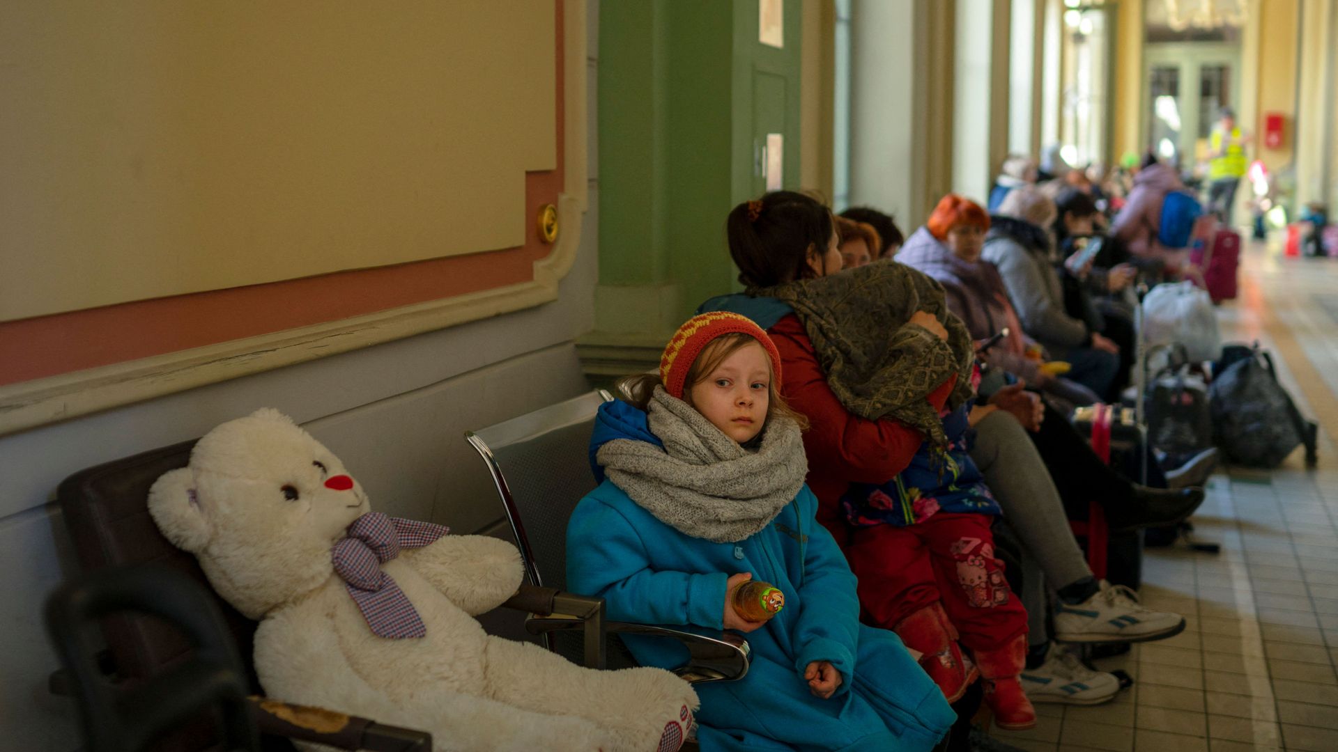 A girl sits next to a stuffed bear as refugees from Ukraine wait in the main railway station in Przemysl, southeastern Poland, near the Polish-Ukrainian border