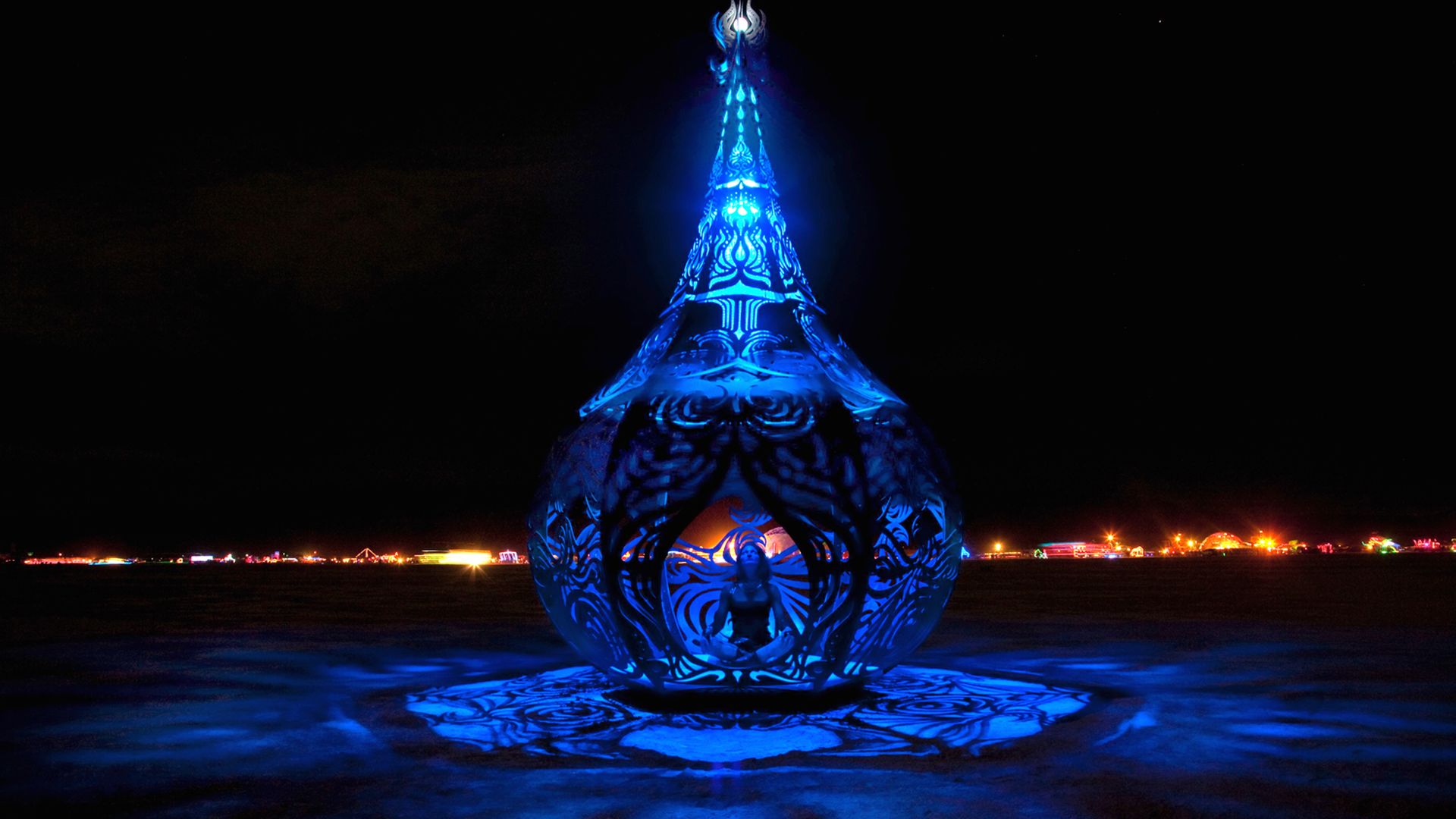 A big blue metal sculpture that looks like a giant tent with a woman in the middle