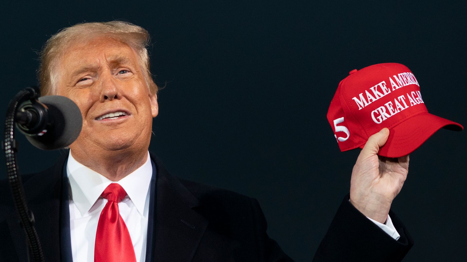 Trump holds a MAGA hat