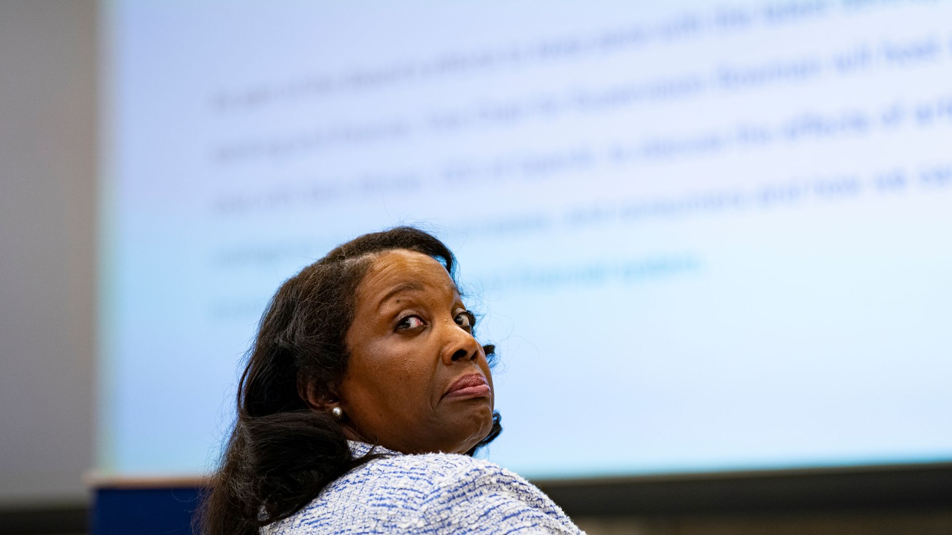 Fed governor Lisa Cook, looking over her shoulder with text on a screen in front of her. 