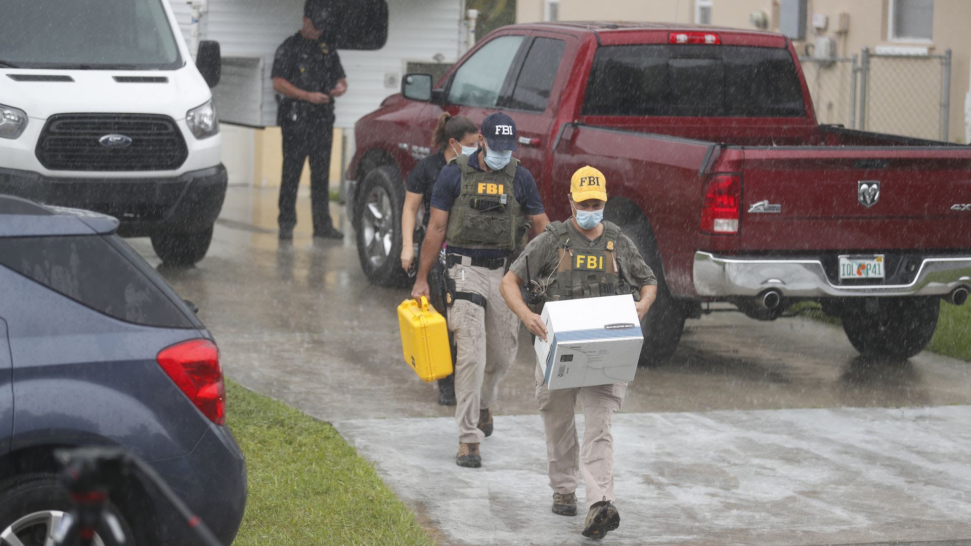 FBI agents walk through the rain with boxes of evidence taken from the North Port family home of Brian Laundrie.