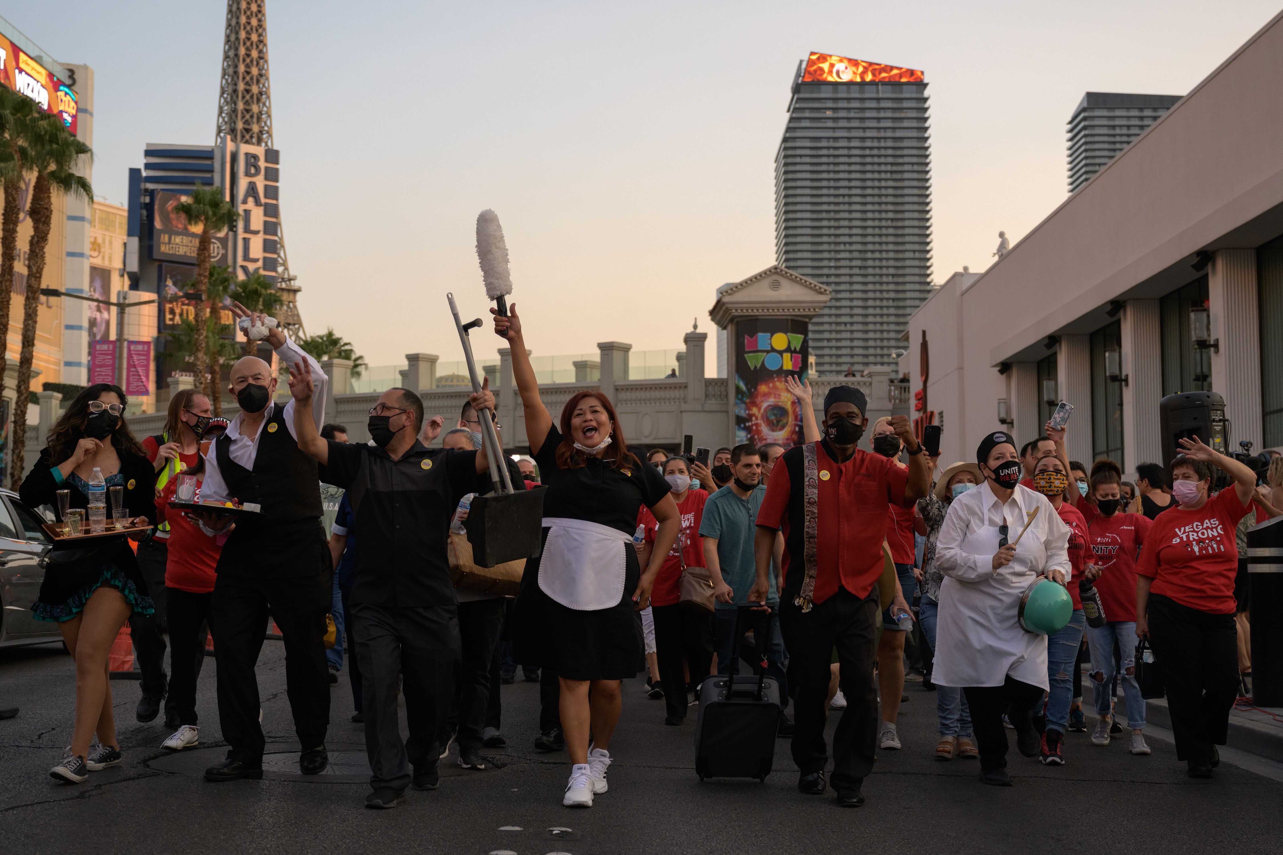 People dressed in hotel and restaurant uniforms march down the Las Vegas Strip at sunset.