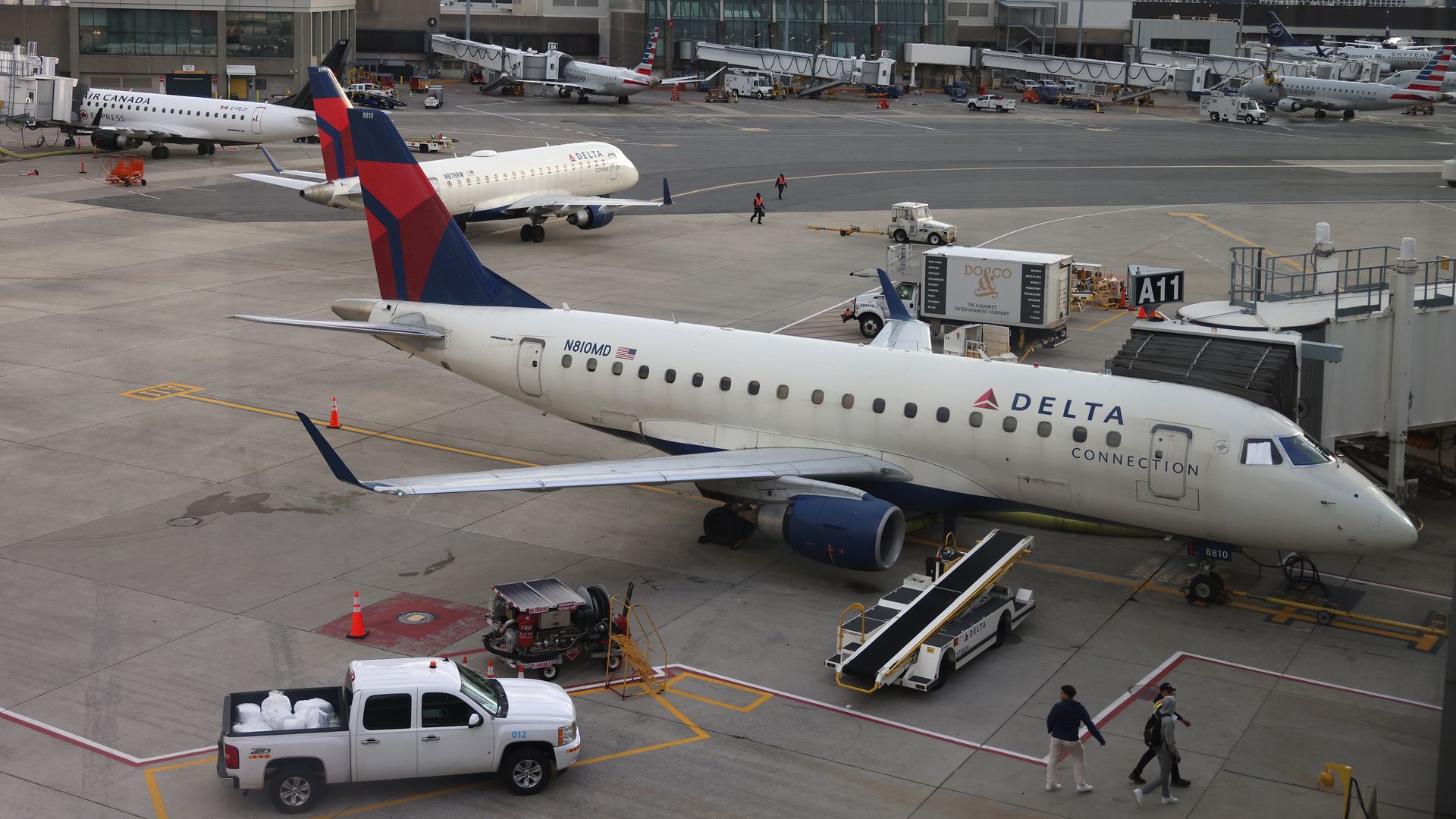 Workers walk past Delta aircraft on the tarmac at Logan Airport on November 11, 2025.