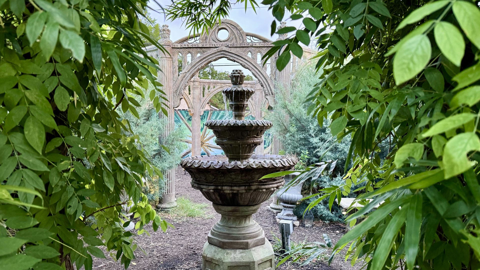 A photo of a fountain surrounded by greenery.