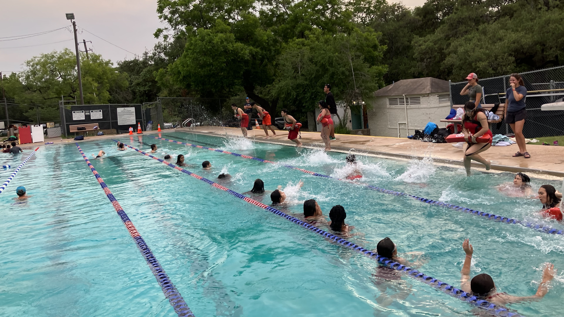 Lifeguard trainees jump into water to practice rescues during a lifeguard class at a pool in Austin.