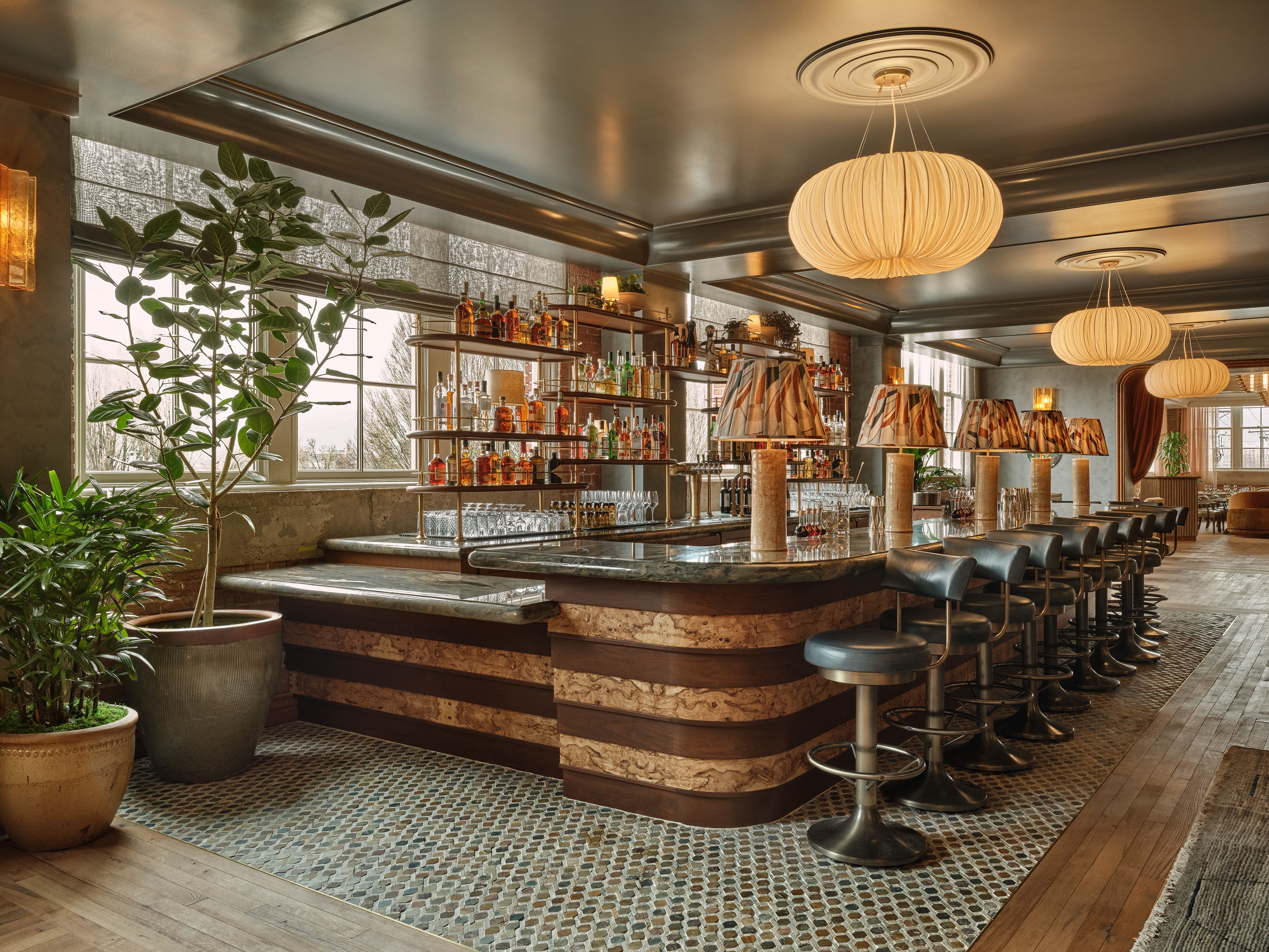 A photo of a large countertop bar with barstools and pendant lights.